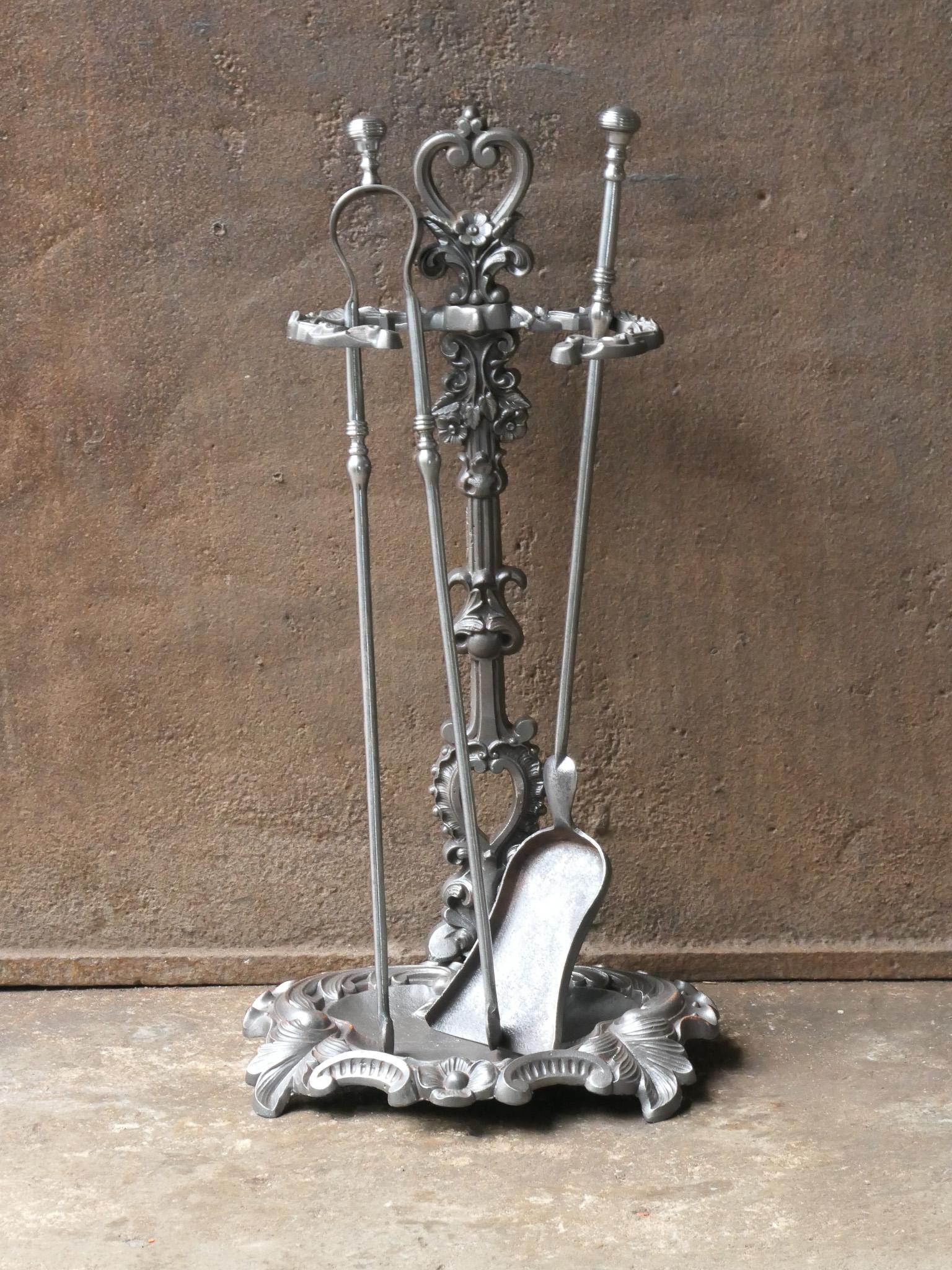 Französisches Kaminbesteck aus dem 19. Jahrhundert. Zeitraum Napoleon III. Das Werkzeugset besteht aus einer Zange, einer Schaufel und einem Ständer. Die Werkzeuge sind aus Schmiedeeisen und der Ständer aus Gusseisen gefertigt. Das Set ist in einem
