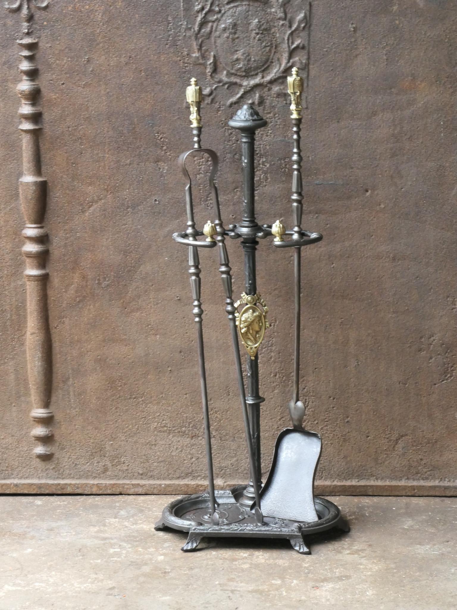 19th century French fireplace tool set. Napoleon III period. The tool set consists of tongs, shovel, and a stand. The tools are made of wrought iron with brass handles and the stand of cast iron also with brass details. The set is in a good