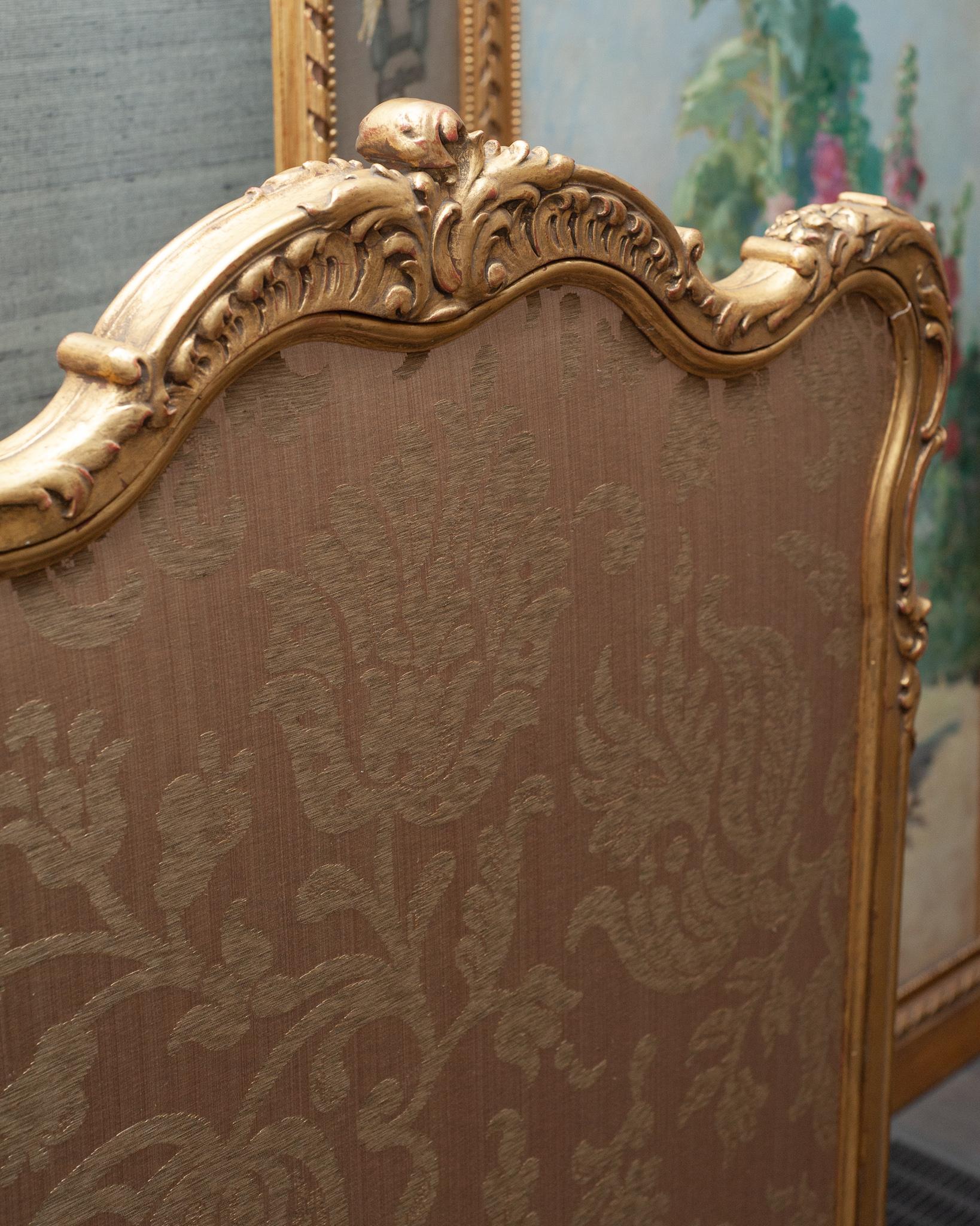 A beautiful antique French Napoleon III large fireplace screen with ornate hand carved wood and gold gilding. Newly reupholstered with damask fabric in tonal beige on front and back panels.