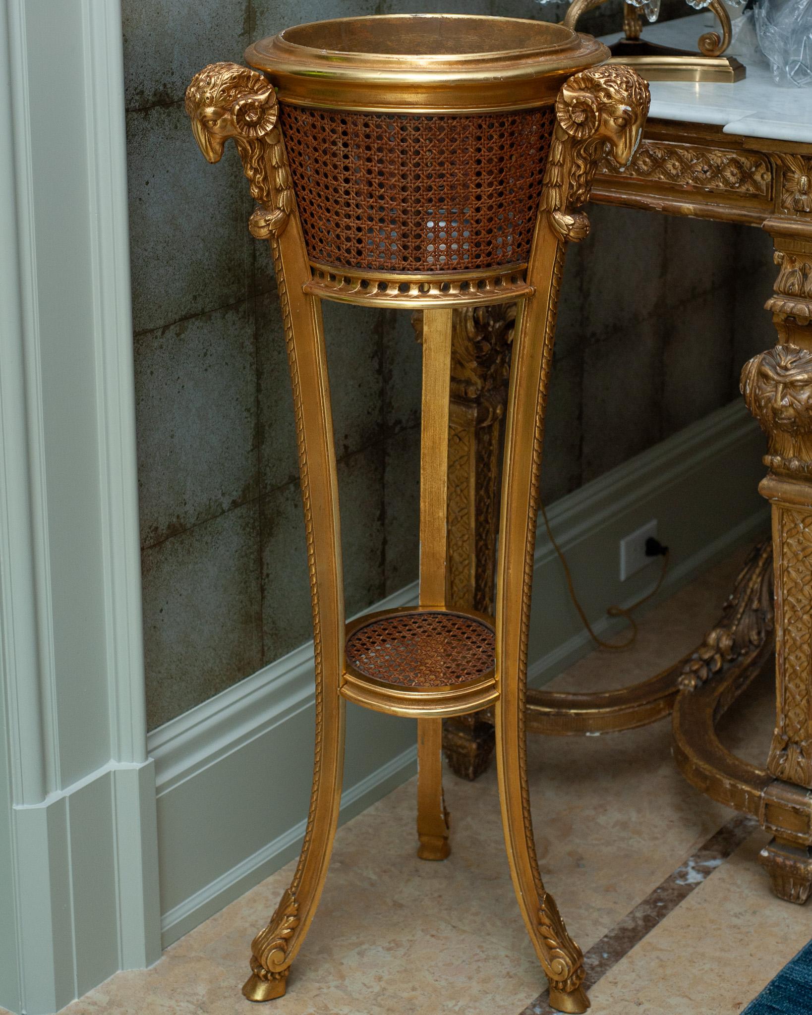 A stunning large scale Antique French Napoleon III era giltwood and cane webbing jardiniere / planter. This jardiniere has beautifully carved details with ornate rams heads at the tops of each leg, original cane webbing, and is entirely gilded. 