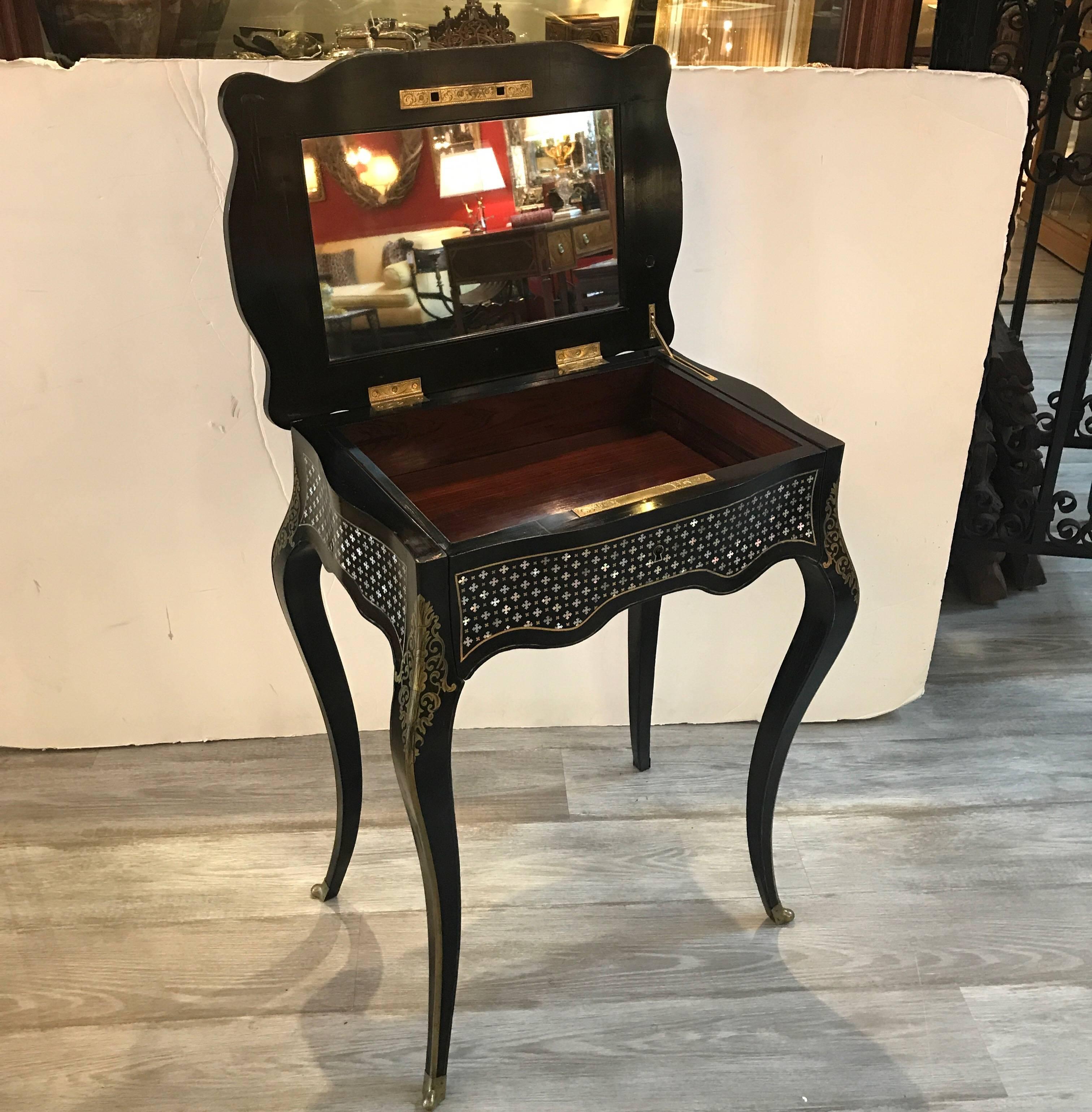 A 19th century ebonized wood and inlaid mother-of-pearl lift top side table. The top lifts to reveal a mirrored top surface which can be used as a small work or dressing table. When the lid is closed there is a single working drawer lined in