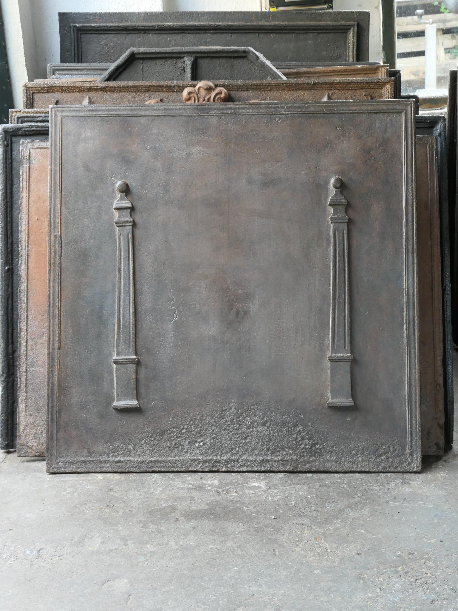 Early 19th century French Neoclassical fireback with two pillars of freedom. The pillars symbolize the value liberty, one of the three values of the French revolution. 

The fireback is made of cast iron and has a brown patina. Upon request it can