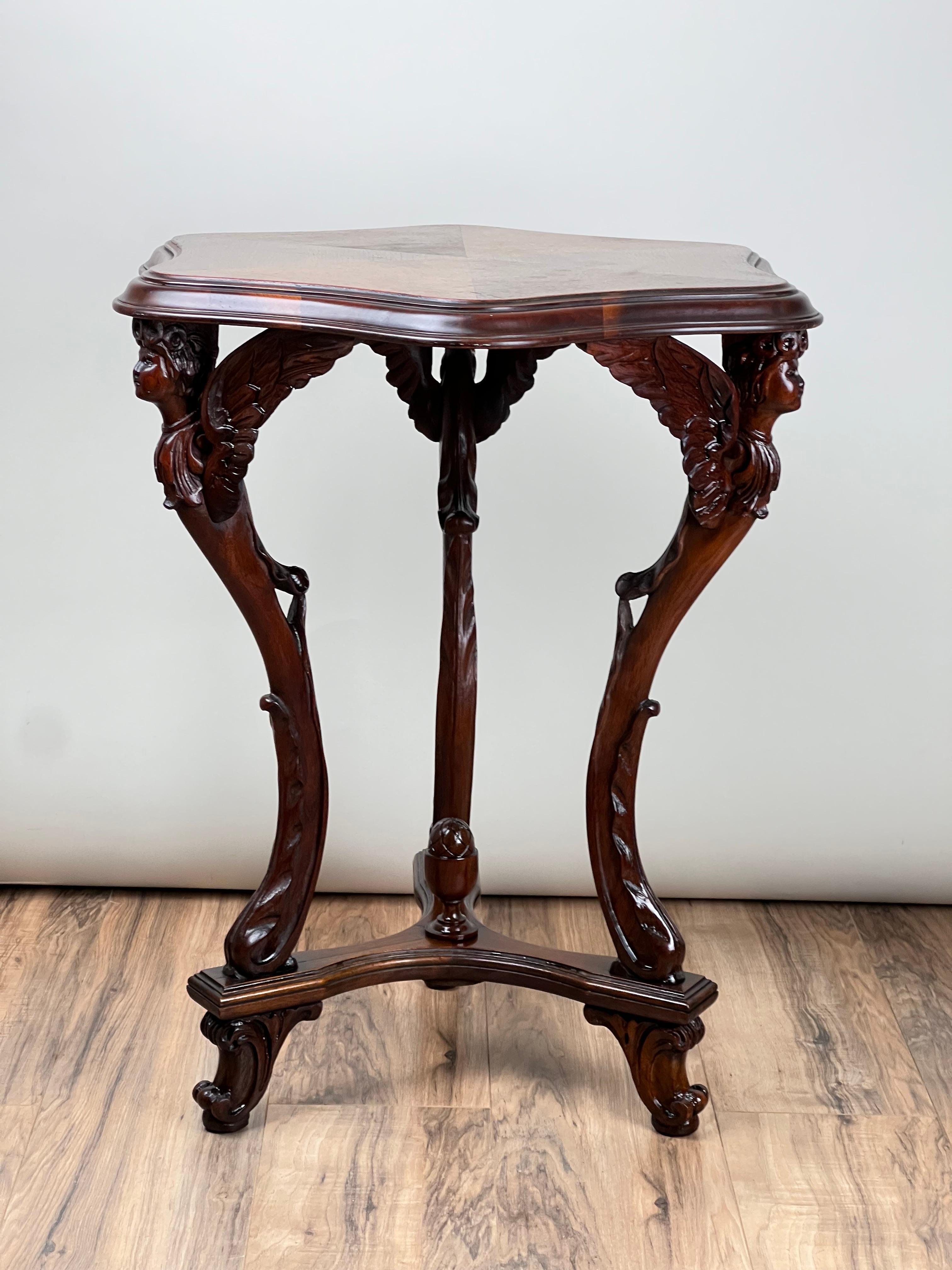 Cette table ancienne à trois pieds en noyer Napoléon III avec épaules d'ange sculptées, datant d'environ 1870, présente un design complexe et distinct qui illustre l'élégance ornementale de l'époque. Le plateau de table façonné est recouvert de