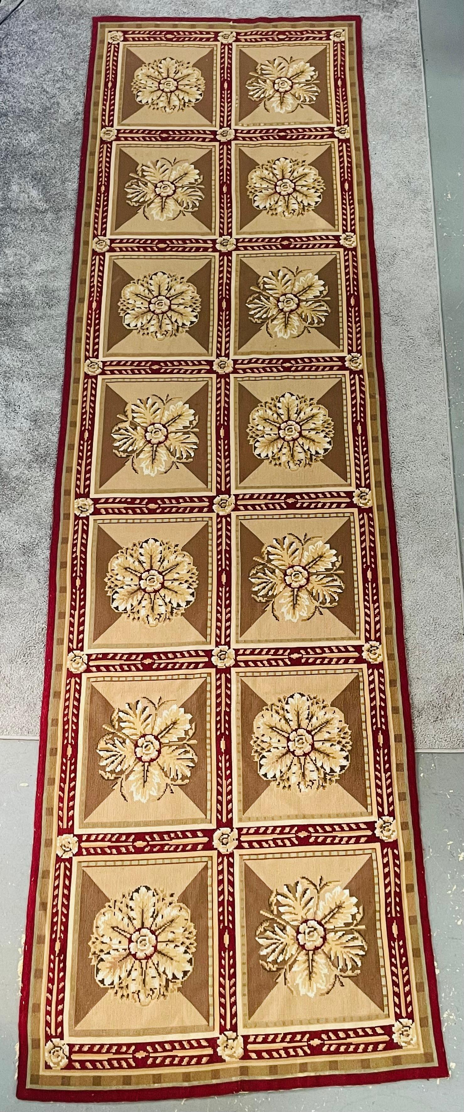An antique French Handwoven needlepoint tapestry or runner featuring a French geometrical patchwork design with a multi-colored background and border, accented with shades of olive, ivory and crimson colors. The elegant tapestry runner will elevate