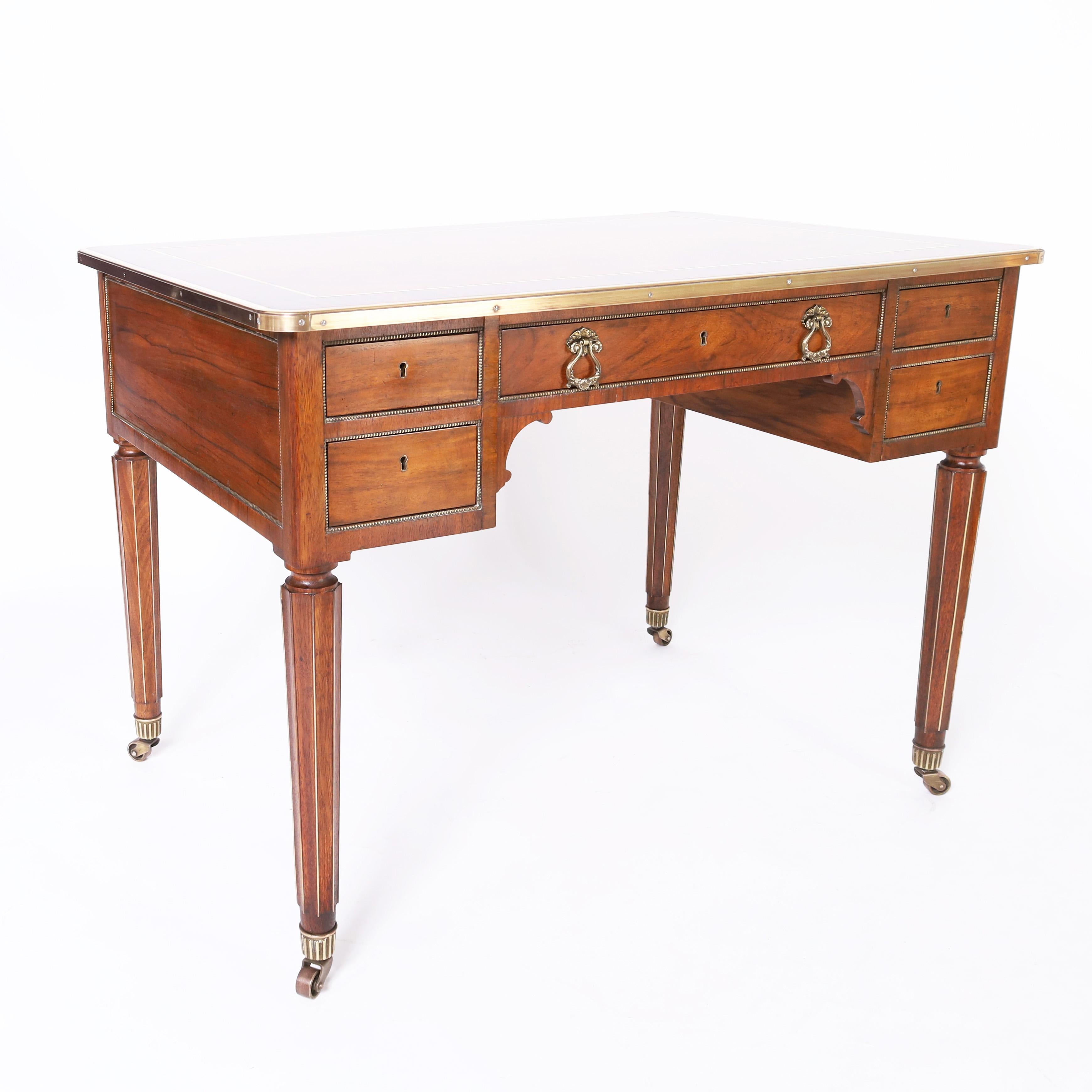 Impressive French writing desk having a dramatic mixed wood top crafted with a burled walnut center crossbanded in zebra wood with brass borders on  a mahogany case having five drawers with beaded brass borders supported by elegant art deco style