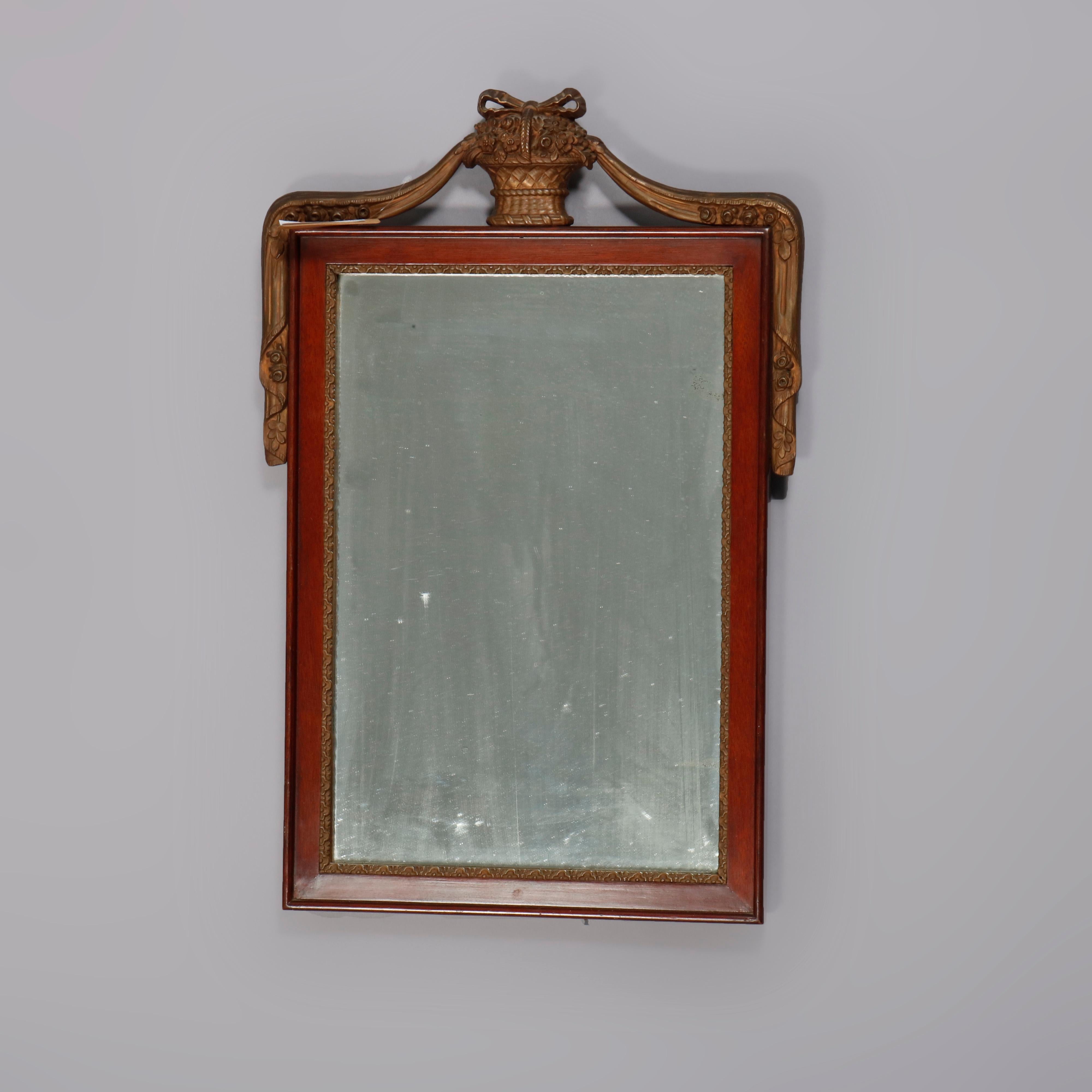 An antique French Neoclassical wall mirror offers giltwood panier de fleurs finial having flanking drapes surmounting mahogany framed wall mirror, circa 1920.

Measures- 24