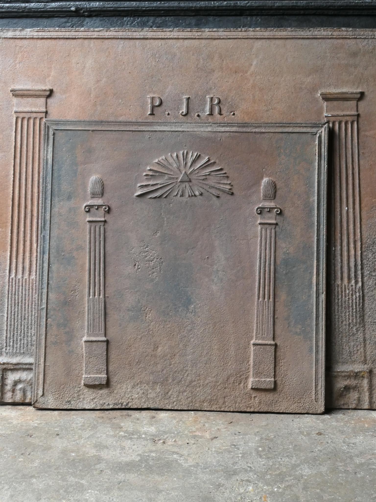 19th century French neoclassical fireback with two pillars of freedom and the masonic eye of providence symbol. The pillars symbolize the value liberty, one of the three values of the French revolution. 

The fireback is made of cast iron and has a