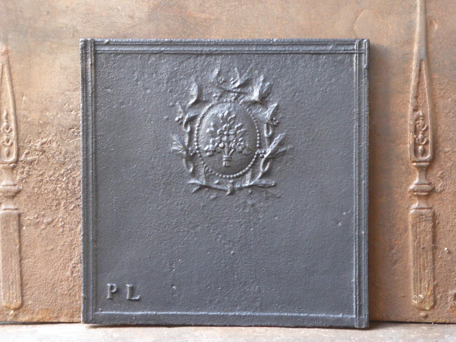 19th century French neoclassical fireback with a floral decoration (which replaced the royal crown after the French revolution). 

The fireback is made of cast iron and has a natural black / pewter patina. The fireback is in a good condition and
