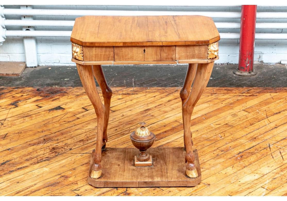 A rare and notable antique French stand with rectangular top with canted corners, over an apron with each corner decorated with carved and gilt leafy masks. The apron with a single flush drawer (with a key). Raised on wonderful tall furry antelope