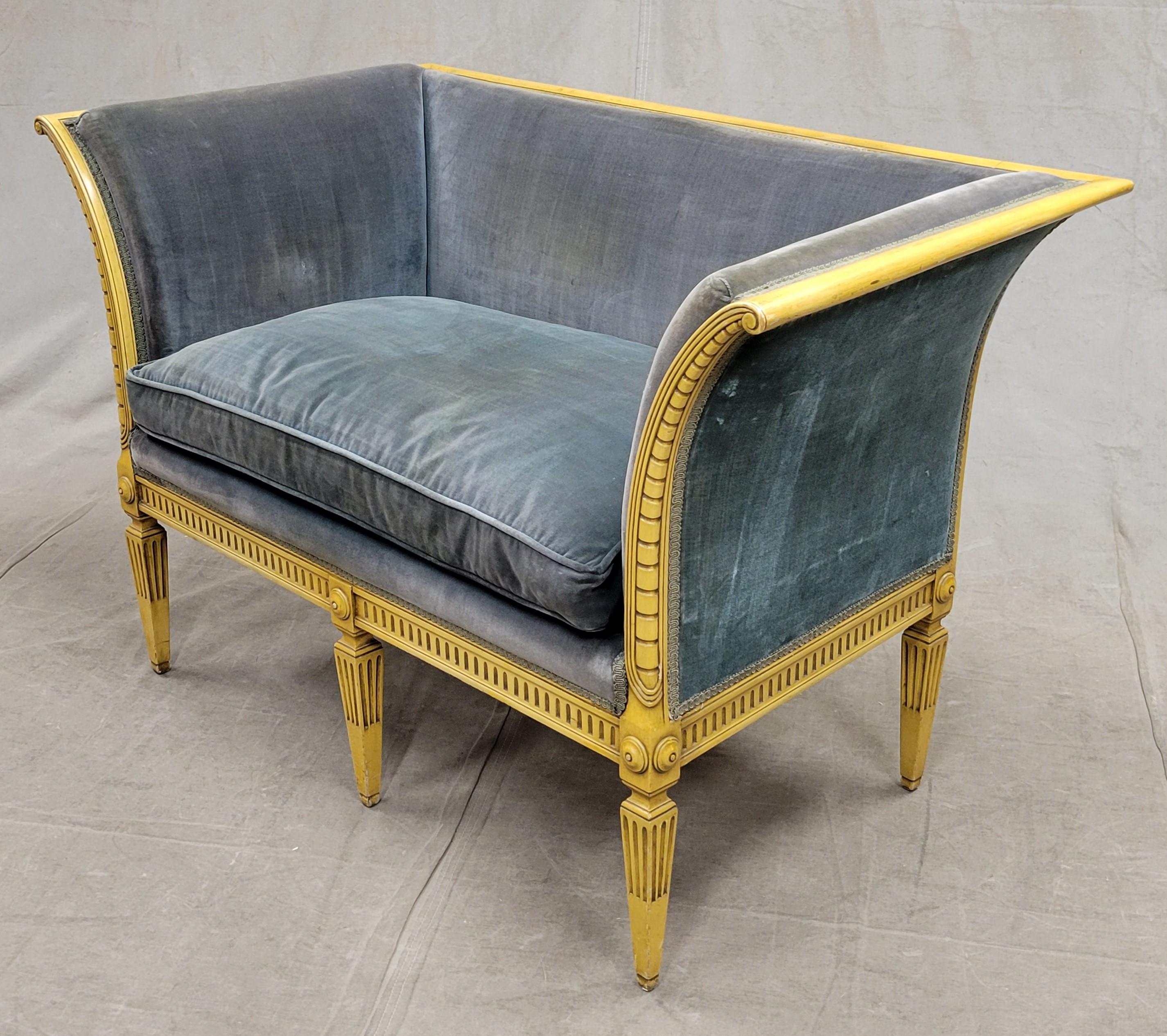 A gorgeous French neoclassical settee loveseat with green velvet upholstery. Likely made between the 1920s and 1940s. Stunning carved wood frame with sweeping arms has the original golden yellow paint. Neoclassical incised dart carving and