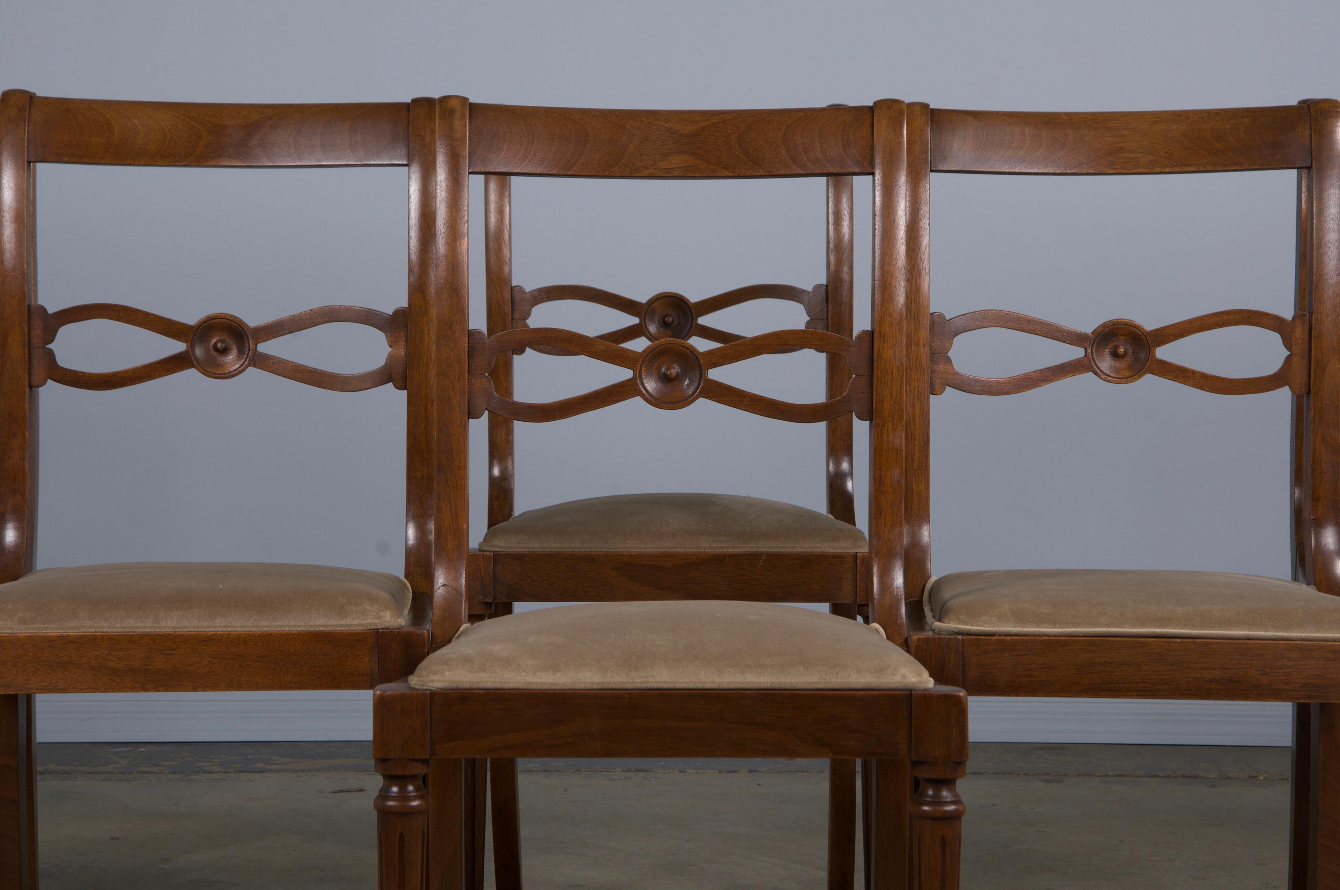 An exquisite set of eight late 19th-century French dining chairs crafted in the Neoclassical Louis XVI style, sourced directly from Provence, France. Each chair is beautifully hand-carved from solid walnut, featuring elegantly curved slat backs that