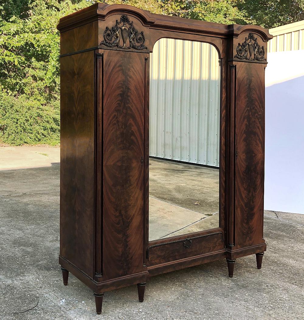 Antique French neoclassical mahogany armoire is a superlative study in architecture that dates back to ancient Greece and Rome! Using exotic imported mahogany to create a flame pattern on the side doors, the expert craftsmen who created this work