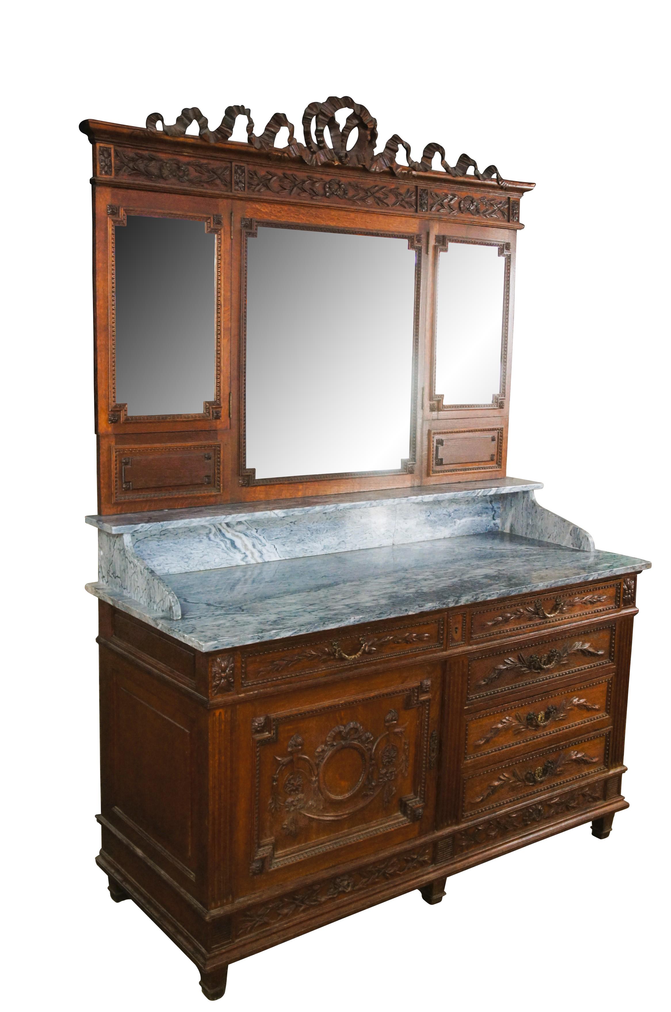 Impressive antique French Louis XV sideboard vanity / server / wash basin / buffet.  Made of quartersawn oak featuring Neoclassical styling with carved ribbon and bow crown over three beveled adjustable mirrors.  Supported by marble top base that
