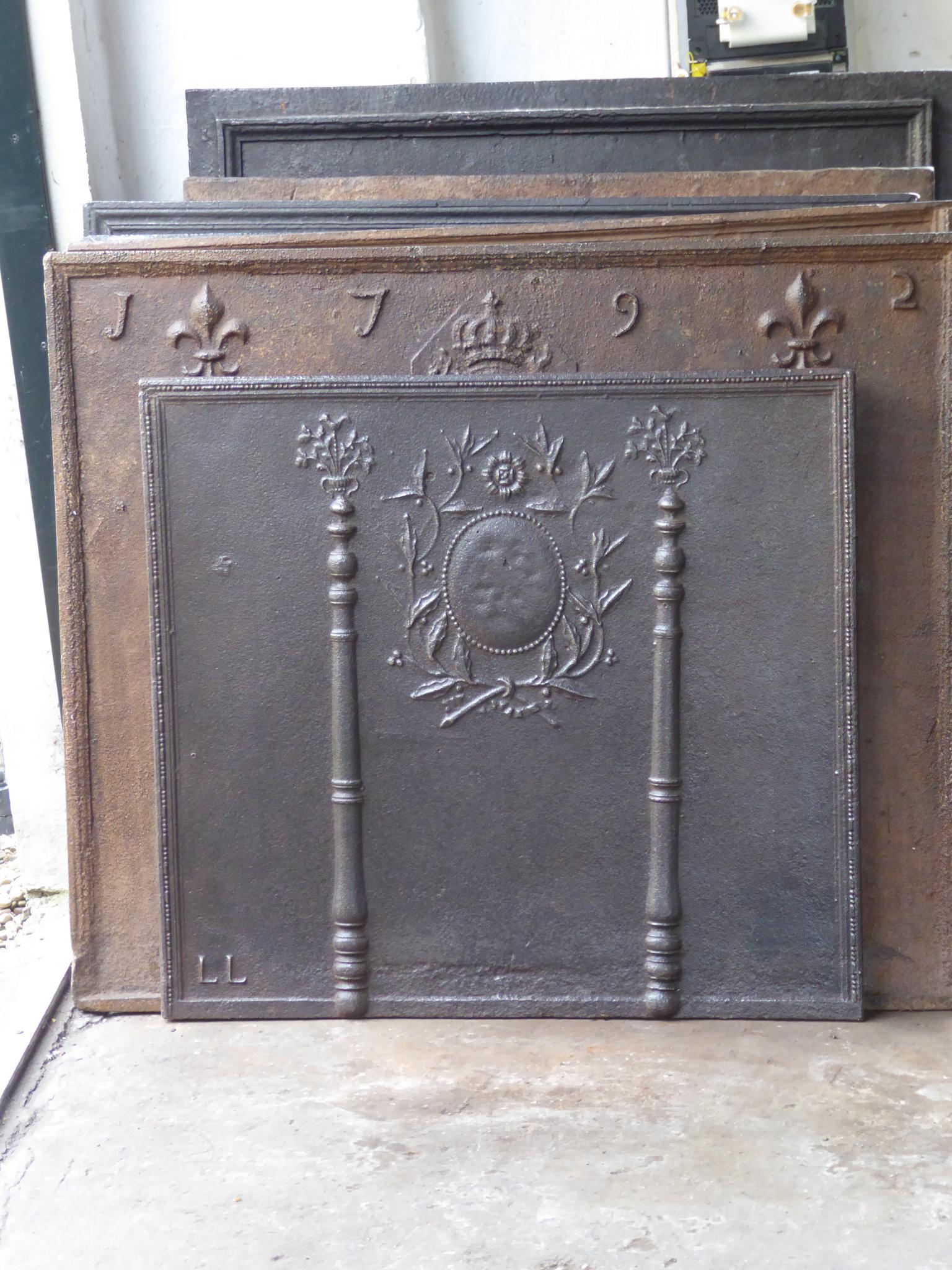 Late 18th or early 19th century French neoclassical fireback with two pillars of freedom. The pillars symbolize the value liberty, one of the three values of the French revolution. 

The fireback is made of cast iron and has a natural brown patina.