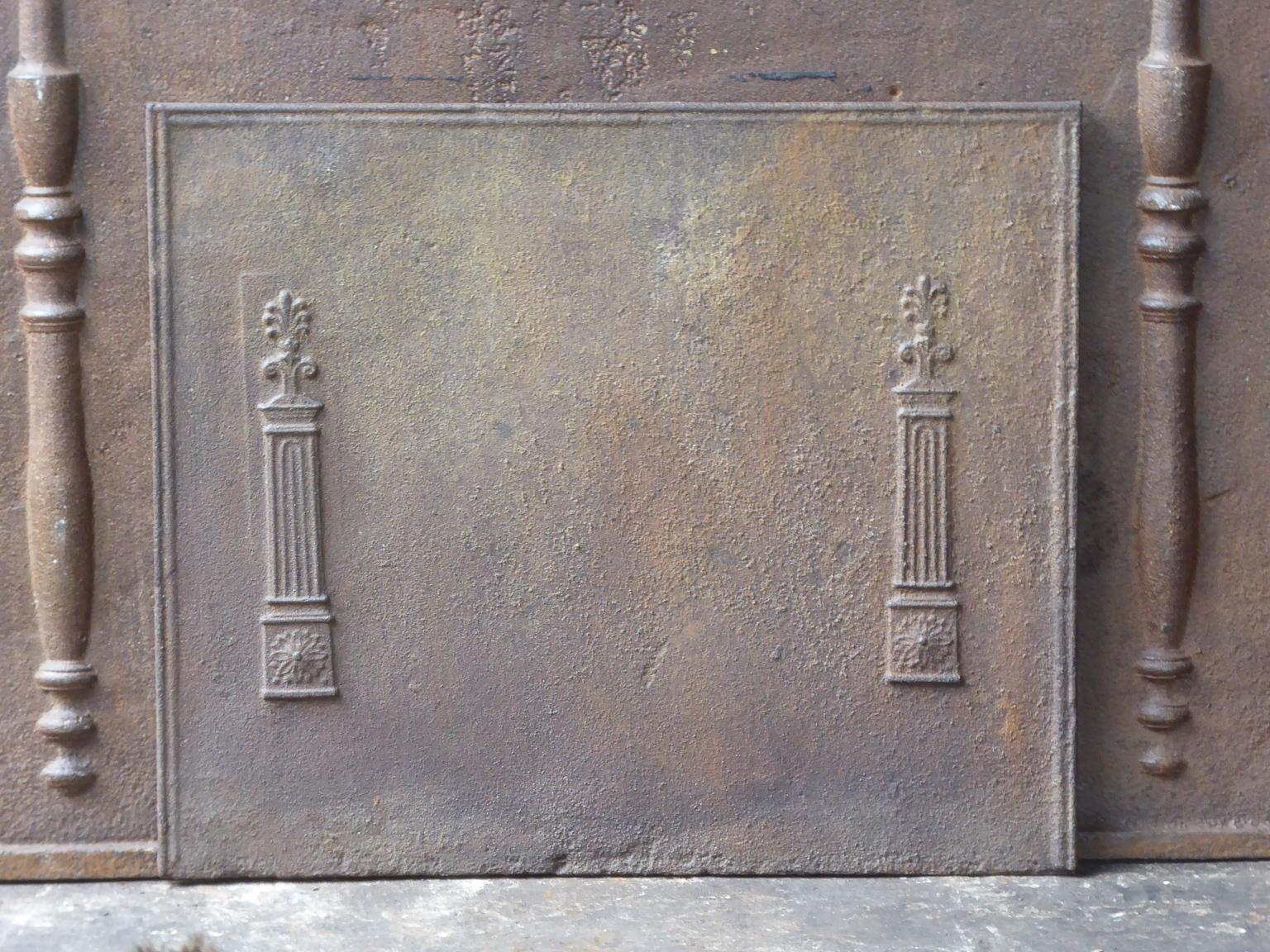 19th century French neoclassical fireback with two pillars of freedom. The pillars symbolize the value liberty, one of the three values of the French revolution. The fireback is made of cast iron and has a natural brown patina. Upon request it can