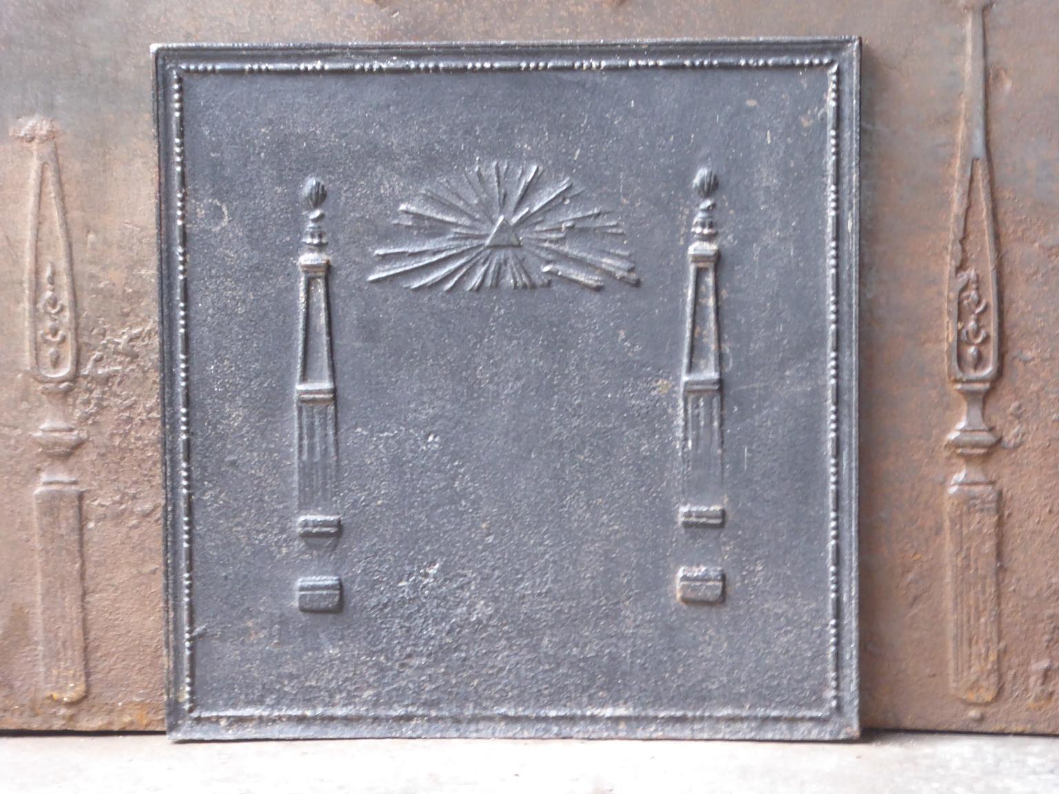 19th century French neoclassical fireback with two pillars of freedom and the masonic eye of providence symbol. The pillars symbolize the value liberty, one of the three values of the French revolution. 

The fireback is made of cast iron and has