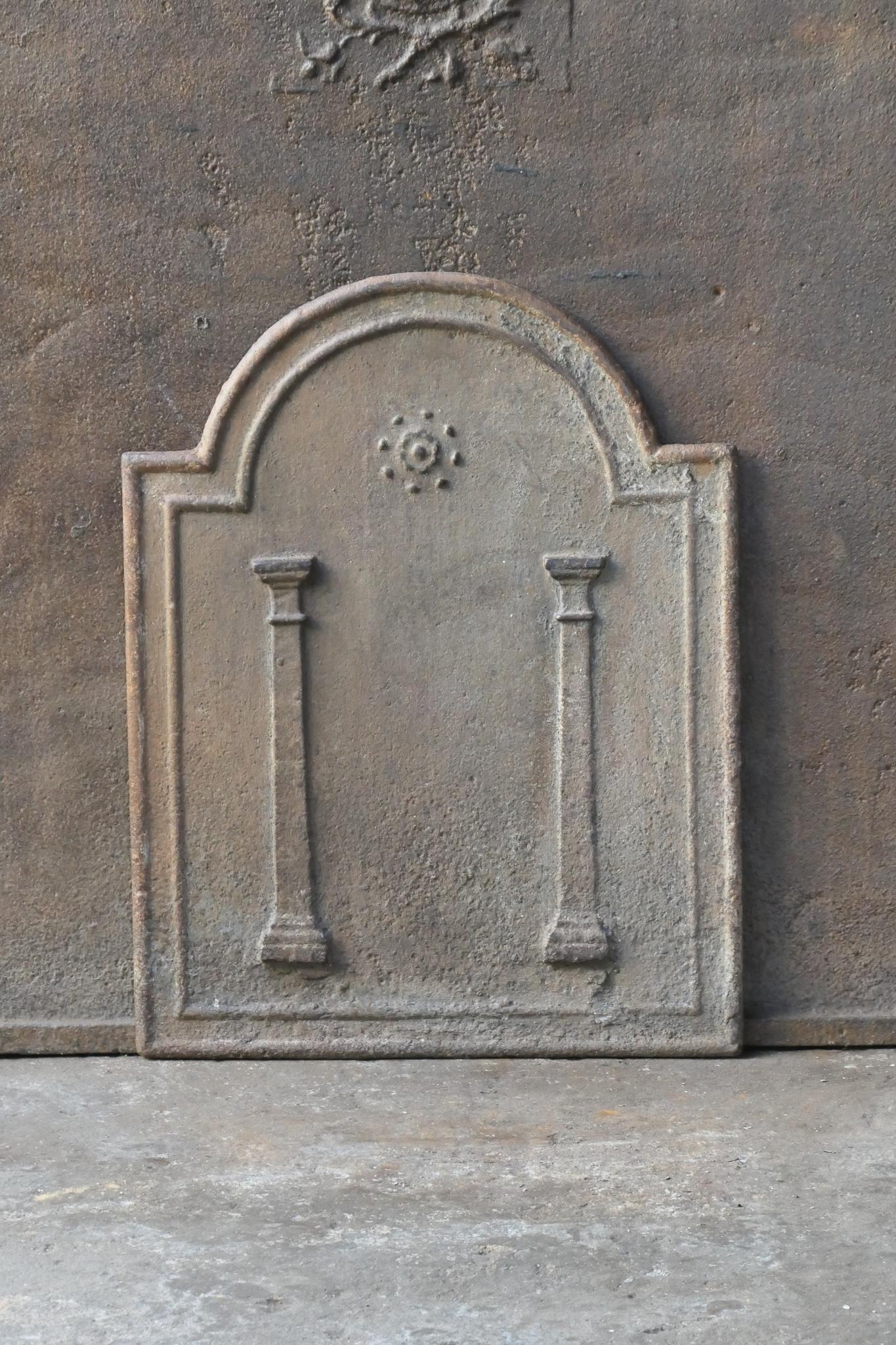 19th century French neoclassical fireback with two pillars of freedom. The pillars symbolize the value liberty, one of the three values of the French revolution. 

The fireback is made of cast iron and has a natural brown patina. Upon request it