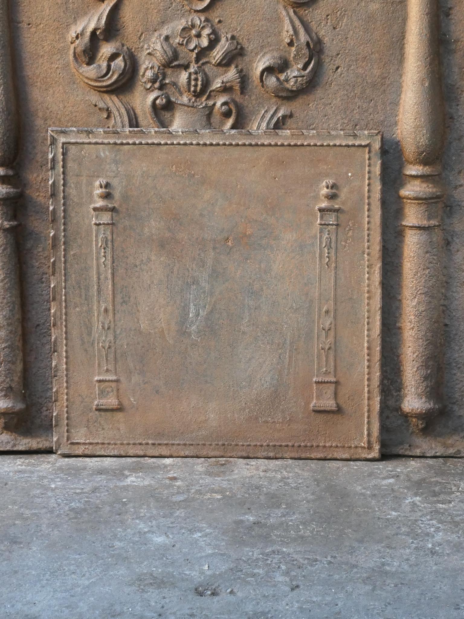 19th century French neoclassical fireback with two pillars of freedom. The pillars symbolize the value liberty, one of the three values of the French revolution. 

The fireback is made of cast iron and has a natural brown patina. Upon request it