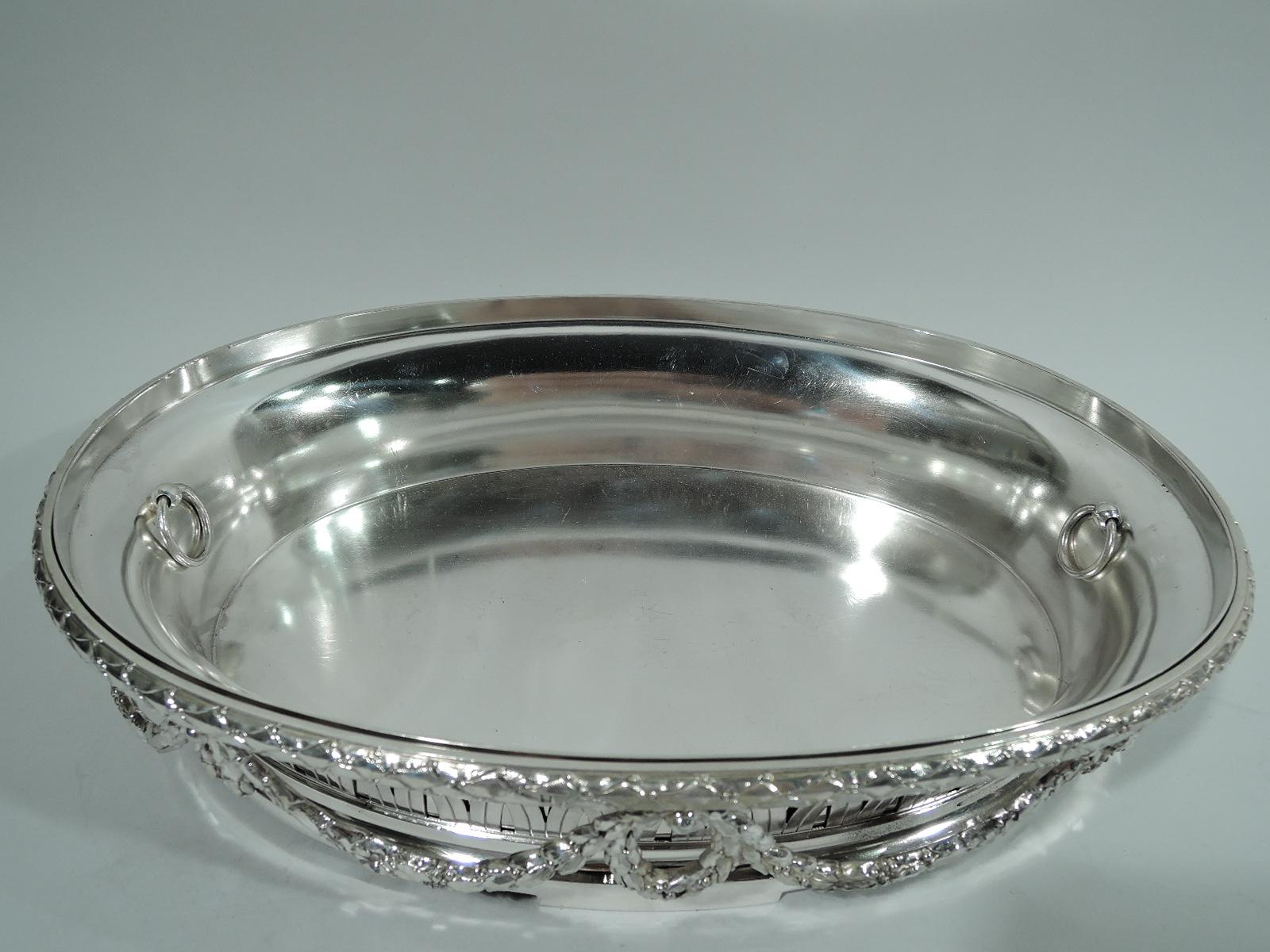 Neoclassical 950 silver jardiniere. Made by Boin-Taburet in Paris, ca 1890. Oval with imbricated leaf-and-berry rim. Sides open interlaced arcade and pendant wreath-and-garland. Open bottom and plain base with rectilinear supports. Original