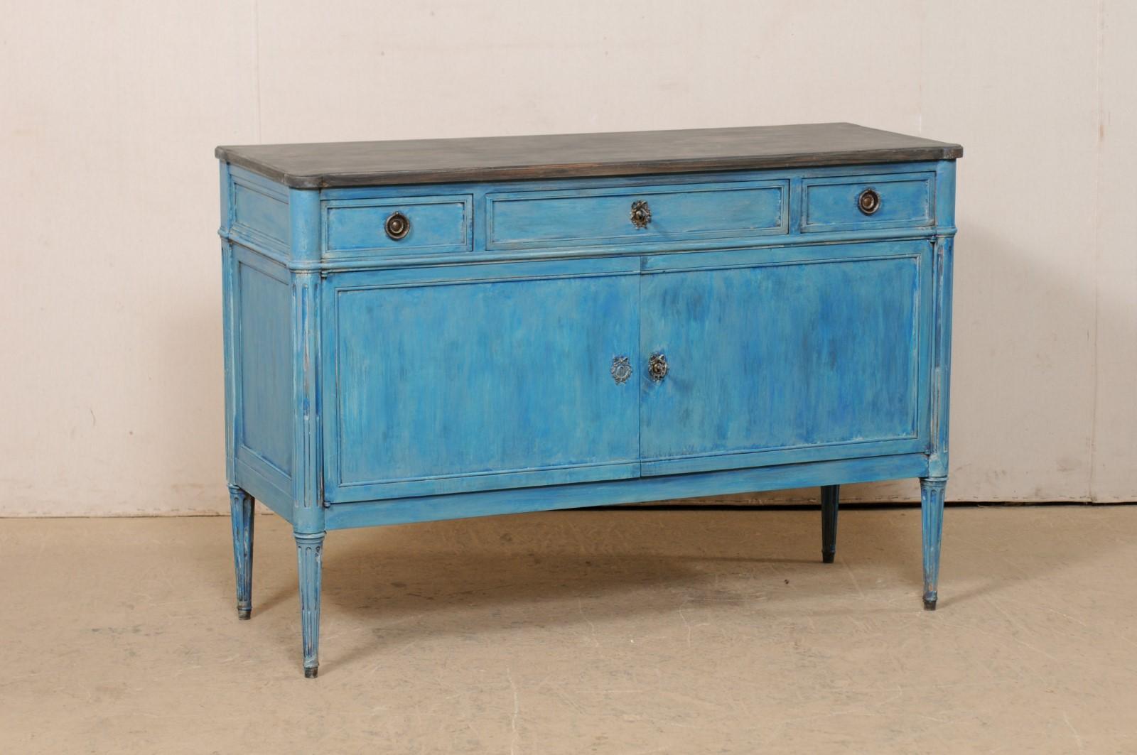 A French neoclassical style carved and painted wood buffet cabinet from the early 20th century. This antique cabinet from France features a rectangular-shaped top top, with pronounced rounded corners, which rests atop a neoclassical style case which
