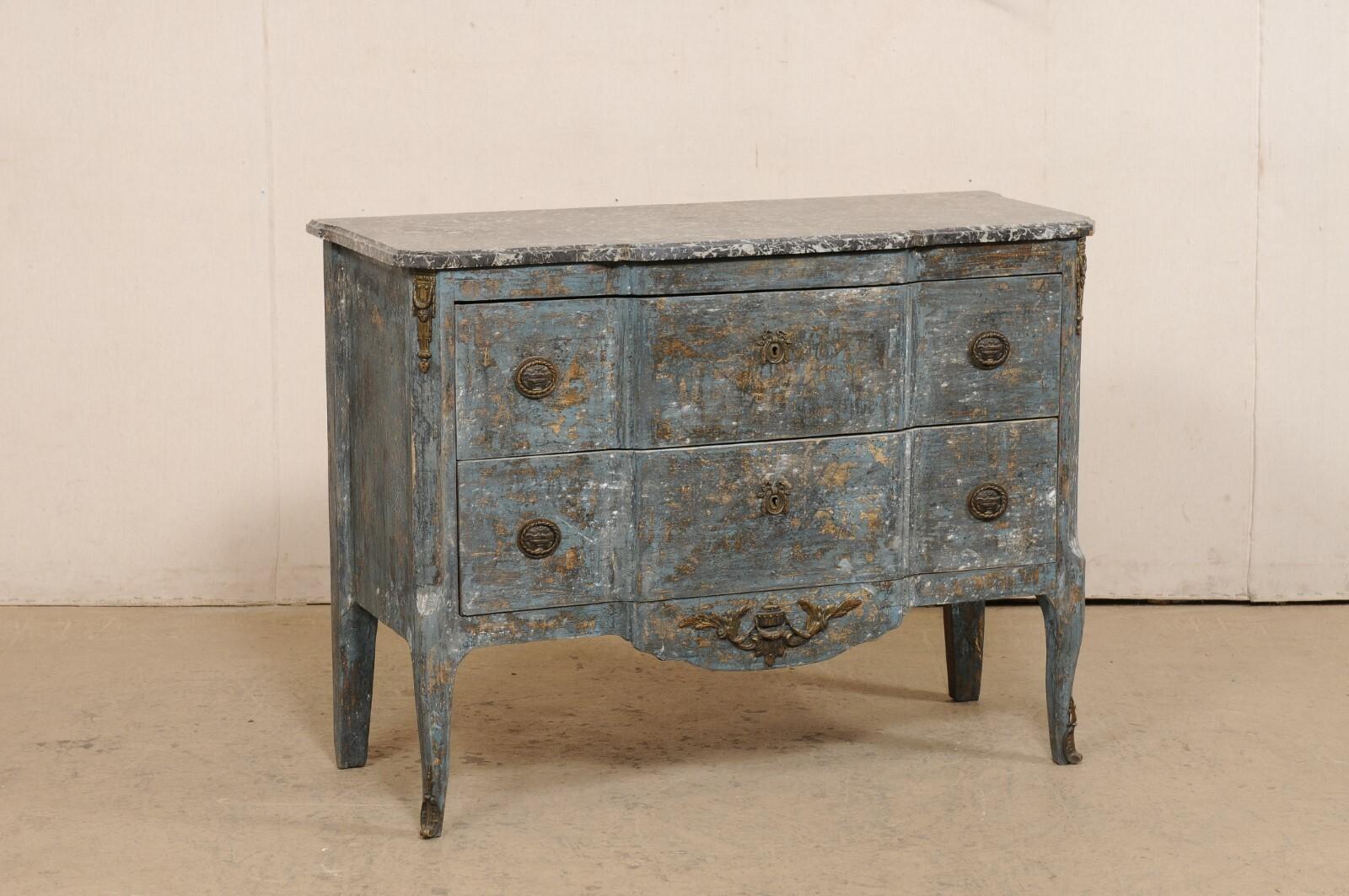 A French two-drawer commode, with shallow break-front design and marble top, from the early 20th century. This antique chest from France has a black marble top which rests atop a wooden chest consisting of two drawers flanking between canted front