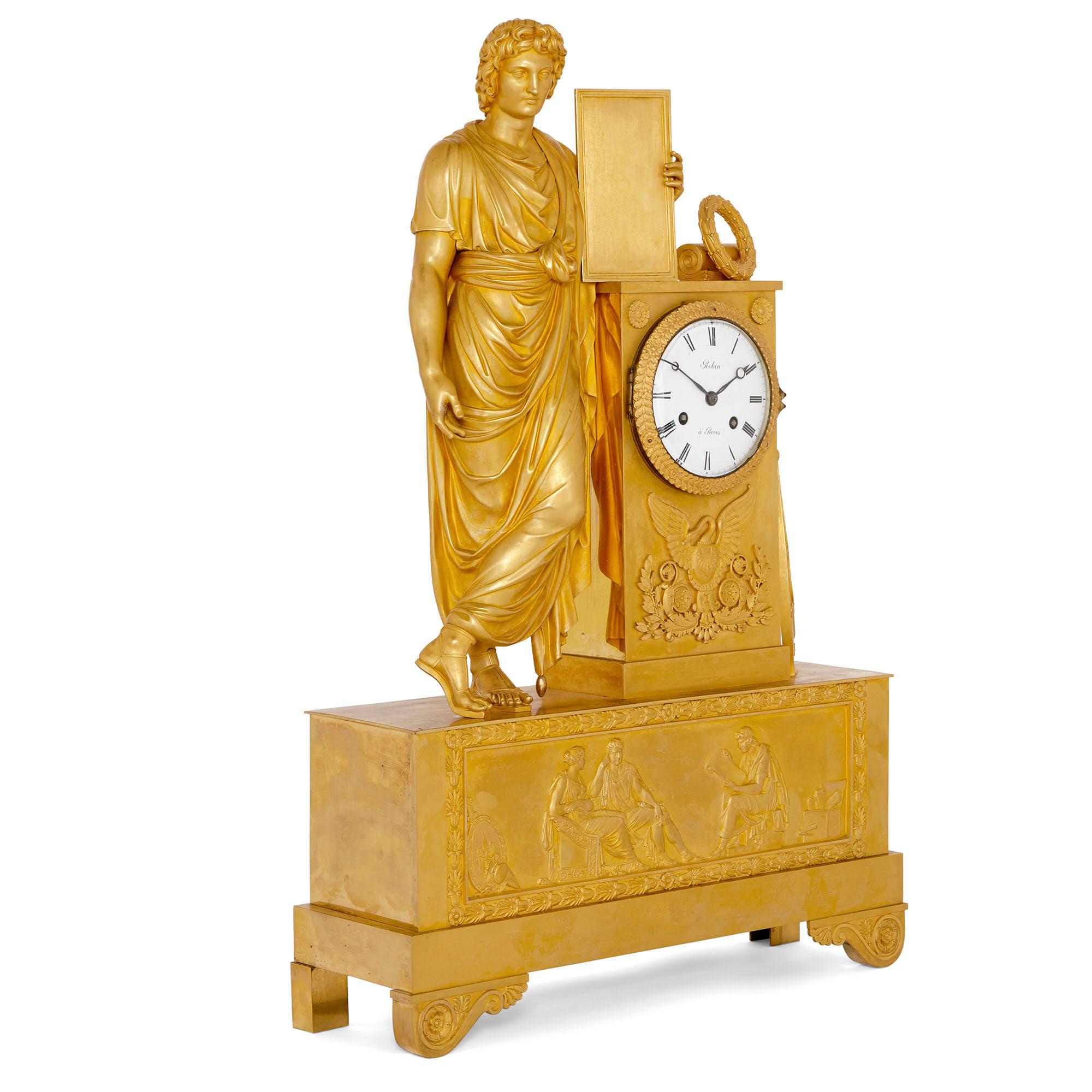 Diese Kaminsimsuhr aus Ormolu (vergoldeter Bronze) ist ein wunderschönes Designerstück mit Flachreliefverzierungen und dreidimensionalen Skulpturen im neoklassischen Stil. 

Die Uhr hat die Form eines hohen, rechteckigen Gehäuses mit einem runden,