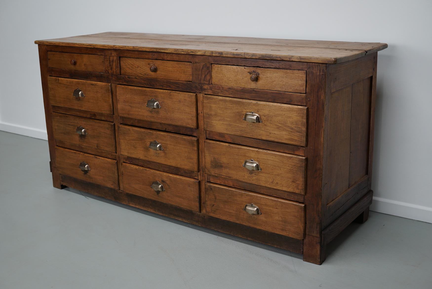 This apothecary cabinet was made around the 1920s in France from oak and beech. It features 12 decent sized drawers in two sizes with metal handles. The interior dimensions of the drawers are: DWH 43 x 38 x 6 cm and DWH 46 x 43 x 14 cm.