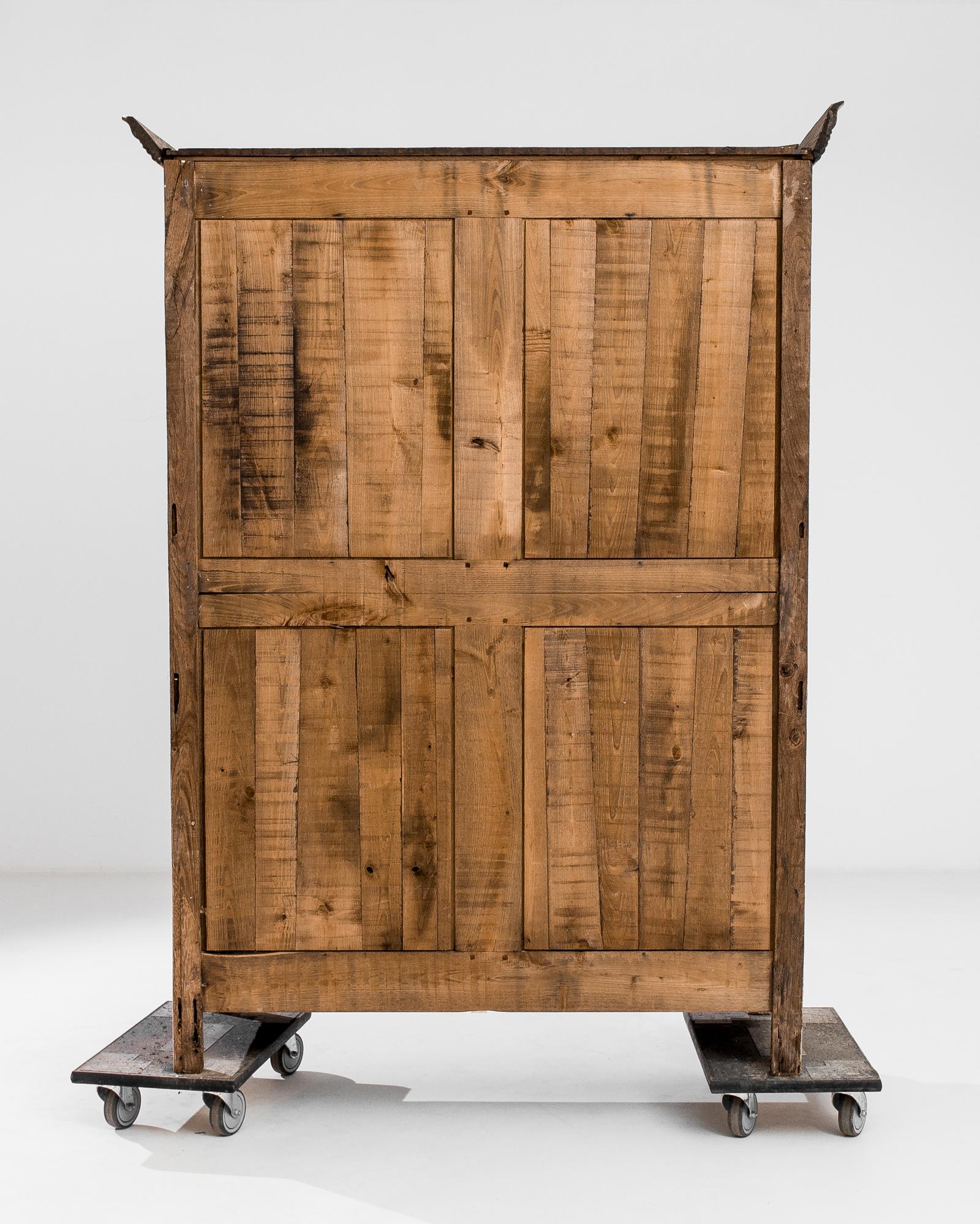 This antique wooden armoire was produced in France, circa 1820. A molded cornice rests firmly on top of the upright case, while simple elegant carvings on the raised doors punctuate the sobriety of the silhouette. The spiral and curves end in a