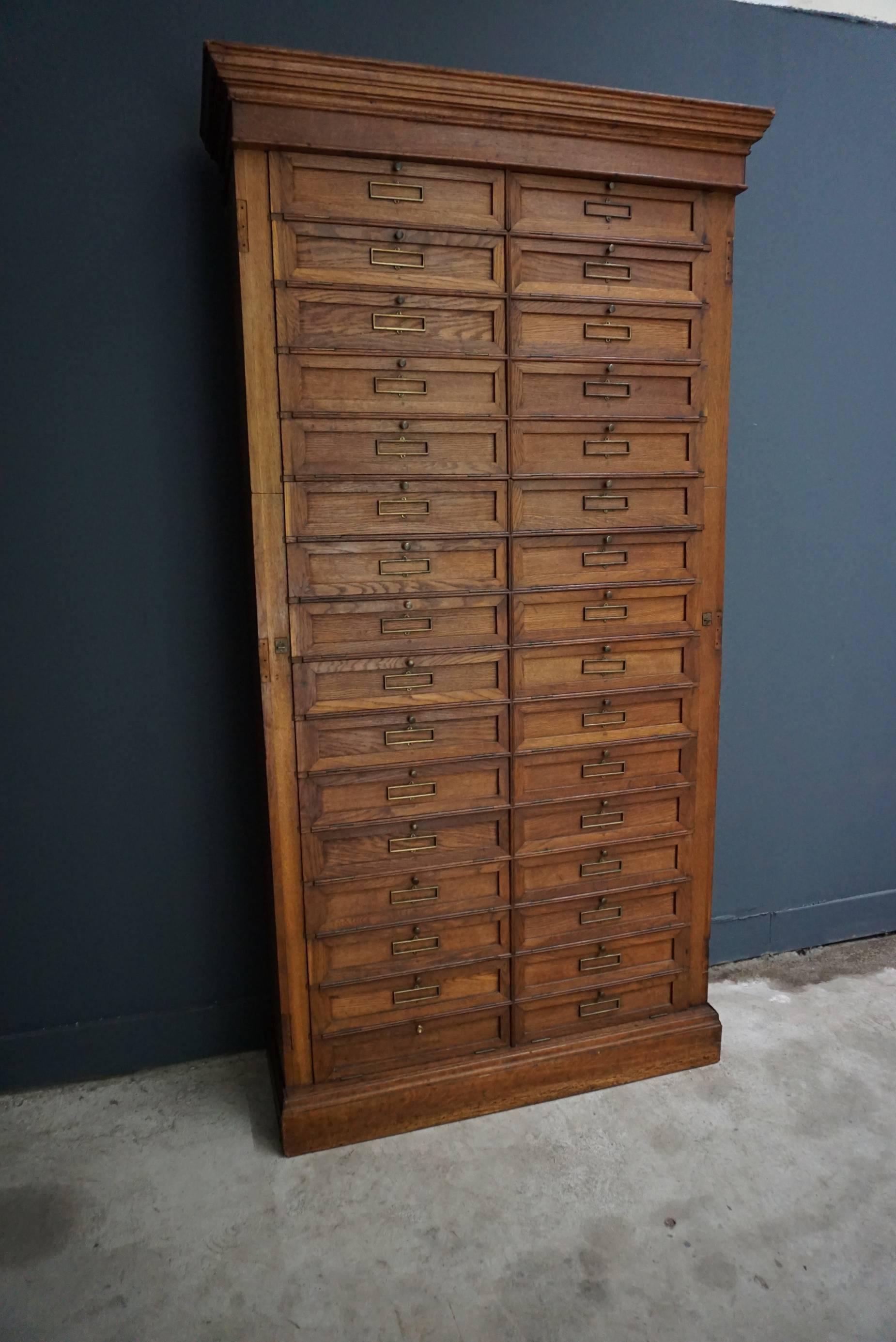 This French oak cabinet was designed and made, circa 1900 in France. It features 32 compartments with drop down doors that were used to store files. It was previously owned and used by the bank of France.