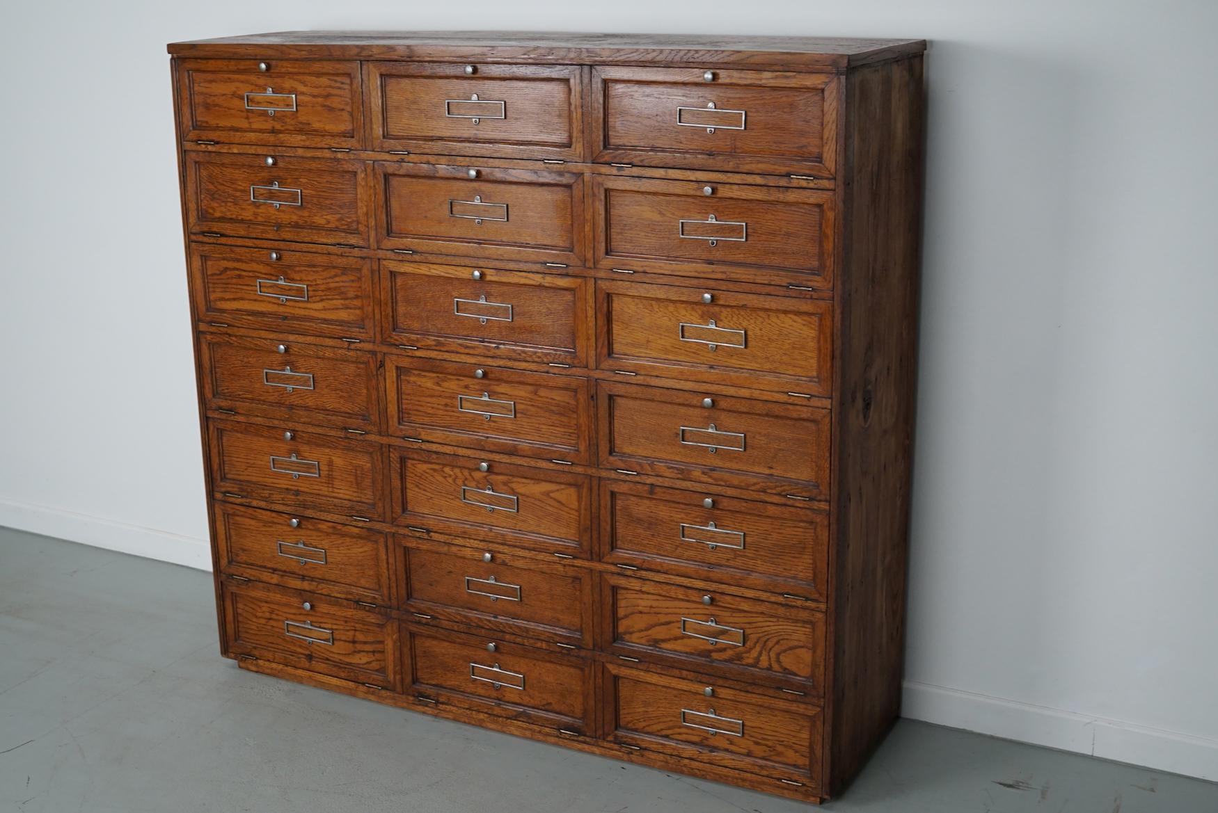 This French oak cabinet was designed and made, circa 1920 in France. It features 21 compartments with drop down doors that were used to store files. It was previously owned and used by the bank of France. The compartment measurements are: D 32 x W