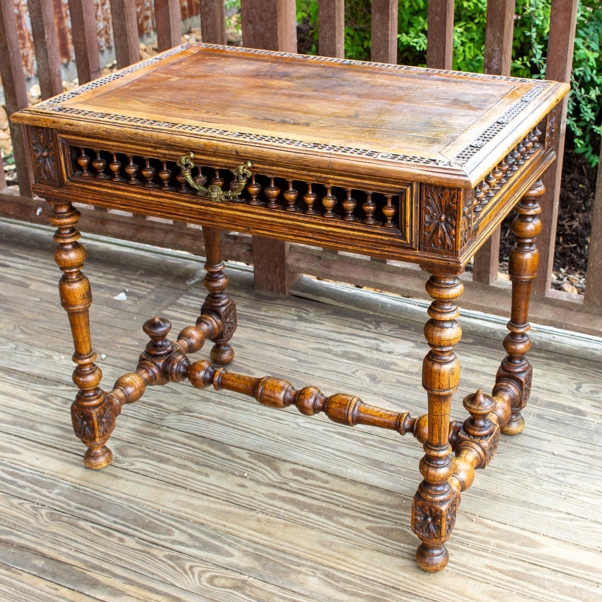 This charming writing desk features a unique design with spindle front drawer and spindle detail at the sides, turned legs, and ornate brass pull on the drawer. The drawer on this desk spans the entire width and offers plenty of interior storage.