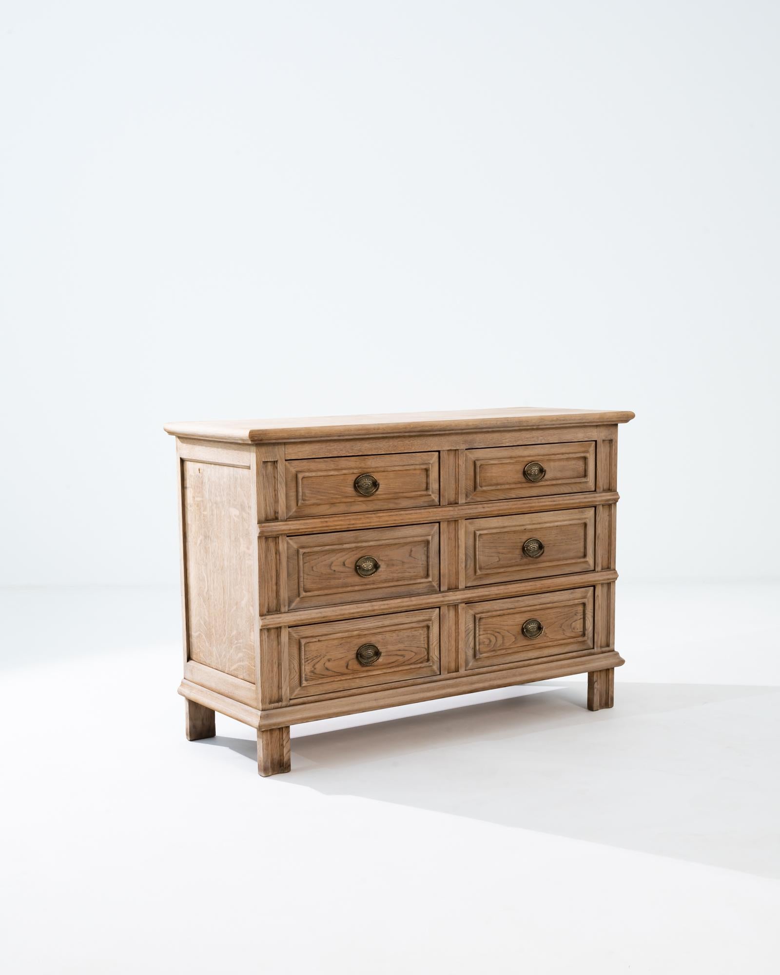 A wooden chest of drawers from France, circa 1900. This chest is composed of six drawers which have been fit with intricate brass drawer handles. Carefully contoured legs add just enough detail to accentuate this chest of drawers ornate form. A