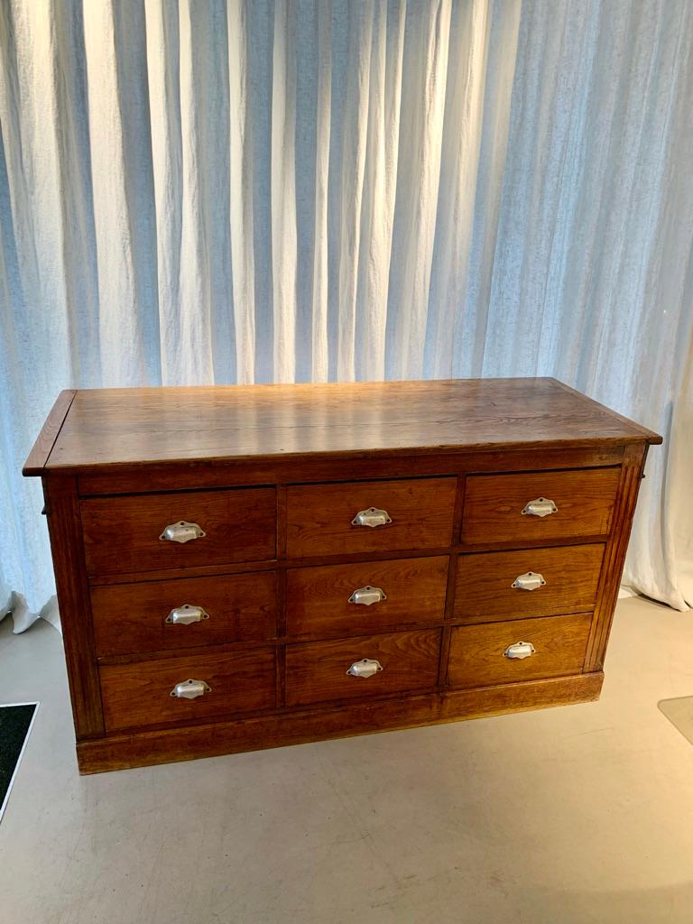 Beautiful antique 1890s French oak wood counter with 9 drawers. The counter has an elegant ornamented front, 9 spacious drawers on the back and a lovely patinated top.   


