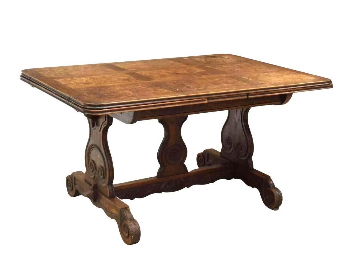 Ancienne table à rallonge en chêne et orme, fin C.C. La table présente un plateau en parquet avec des feuilles de tirage, une base en tréteaux sculptée, se terminant par des pieds en forme d'acanthe à volutes. Cette table ferait également un