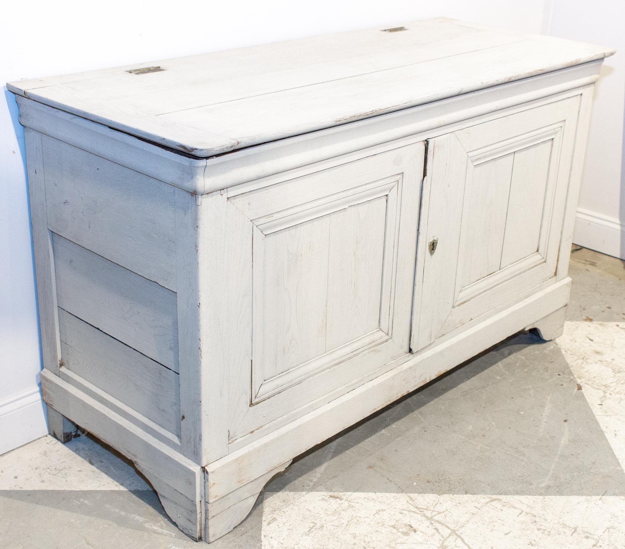 This antique French oak buffet is crafted in solid oak and features a hinged-lid with lower storage accessible by cabinet doors. The piece has been refinished in a light greige wash, which works beautifully in a variety of spaces. The doors do not