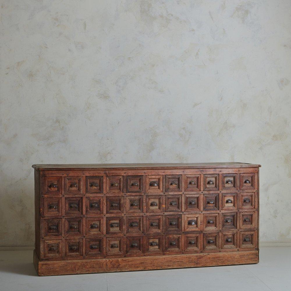 This monumental antique French chest is a storied piece with 44 drawers formerly used to house hardware of all shapes and sizes. It originated from a 120 year old hardware store in central France. It was constructed with oak and pine wood and has a