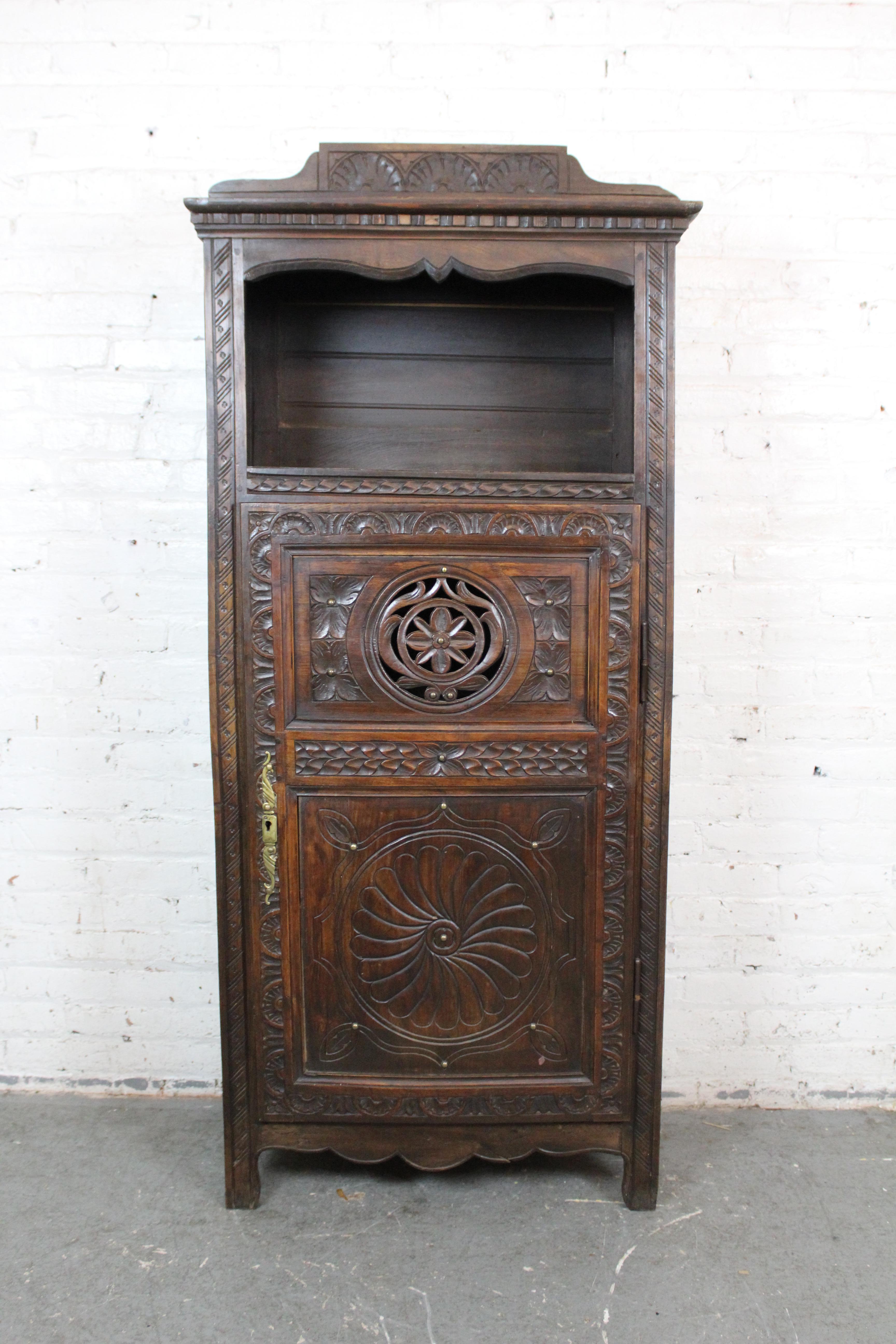 Adopta la encantadora elegancia de la Bretaña francesa del siglo XIX con este impresionante armario antiguo de roble. Este armario de estilo bretón presenta una gran puerta de madera maciza con bellas tallas artesanales que muestran motivos florales