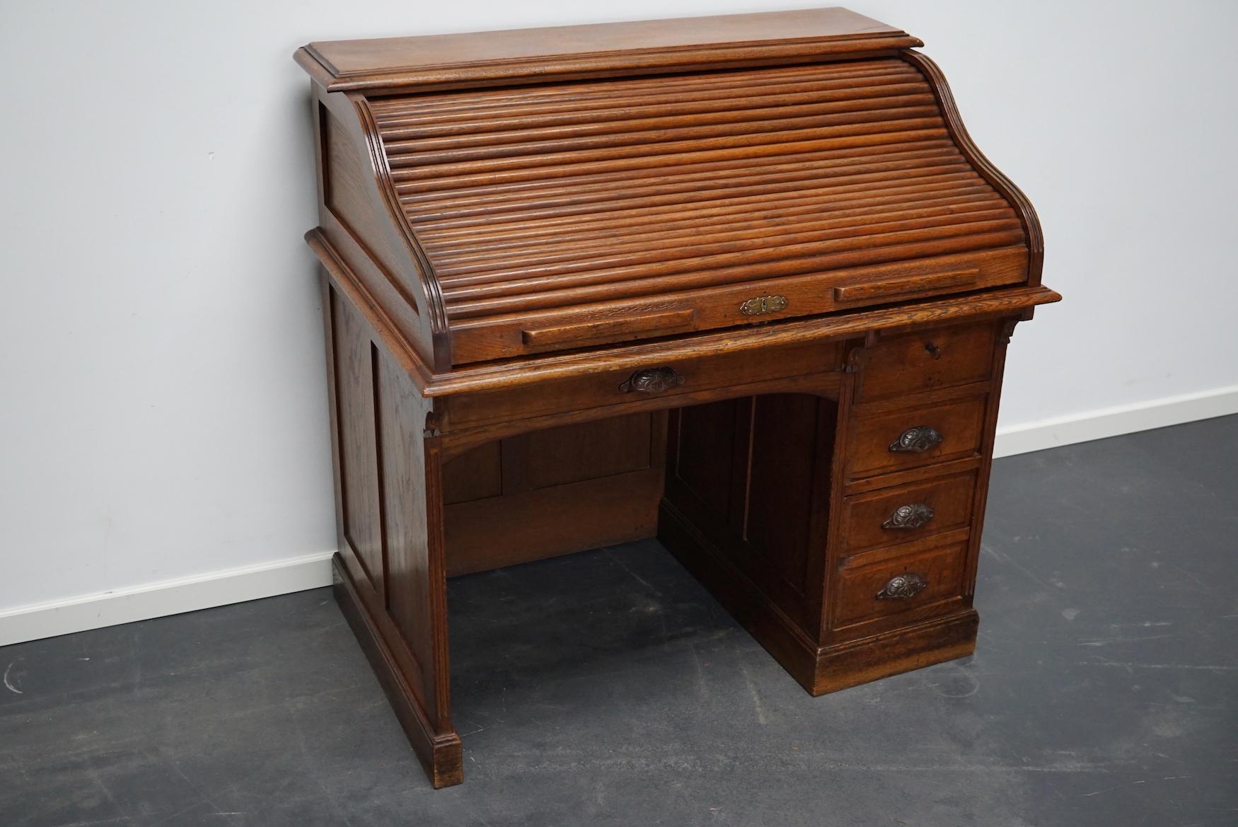 This desk was made around the late 19th century in France. It is made from solid oak with a roll top. It was used in Banque de France in the city Rouen. The desk retained a very nice patina over the years. The height to the worktop is 77 cm and the
