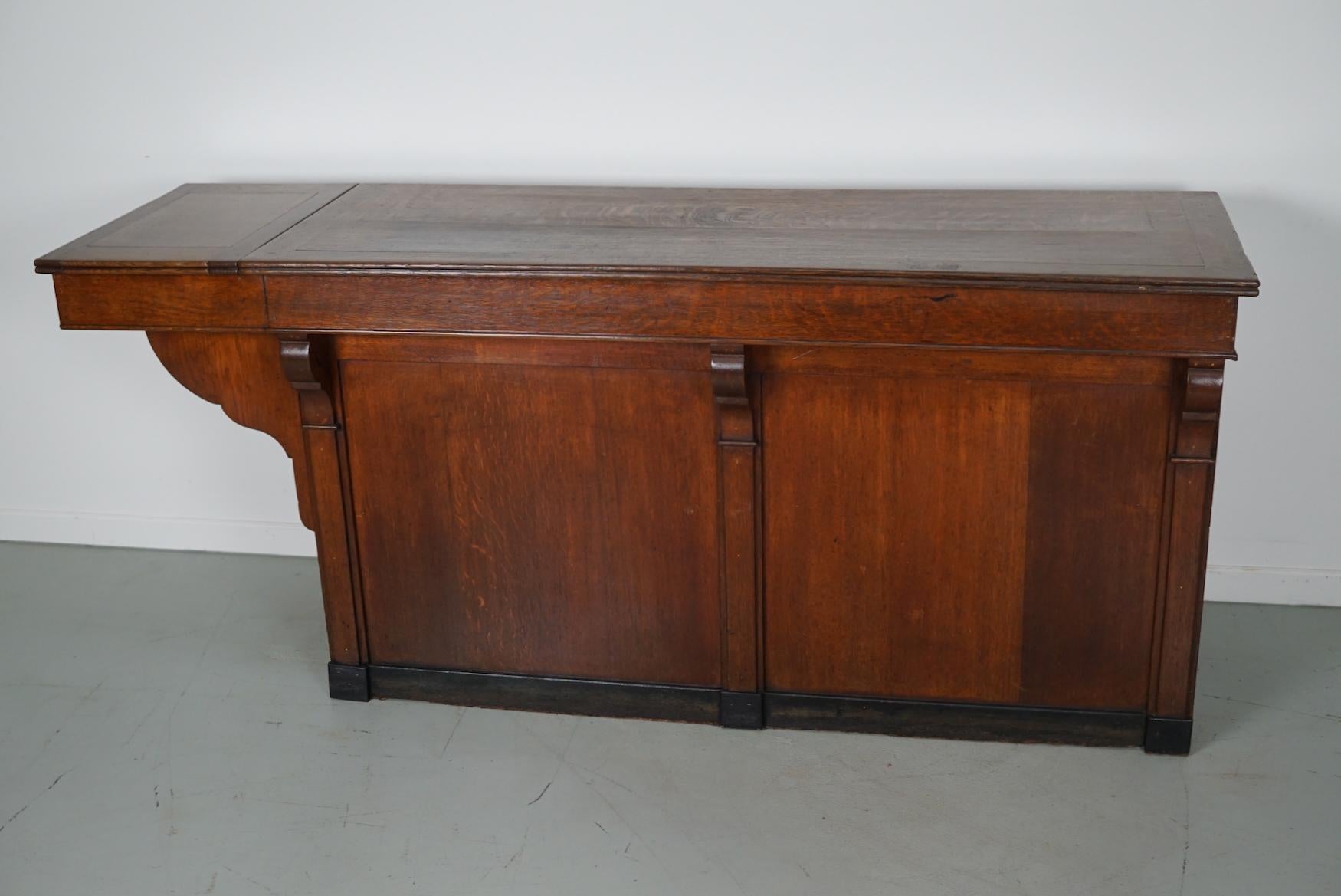 This antique oak shop counter dates from the turn of the century and was made in France. It features an oak paneled frame and four drawers. This shop counter could also be used as a kitchen island / workstation. The interior dimensions of the