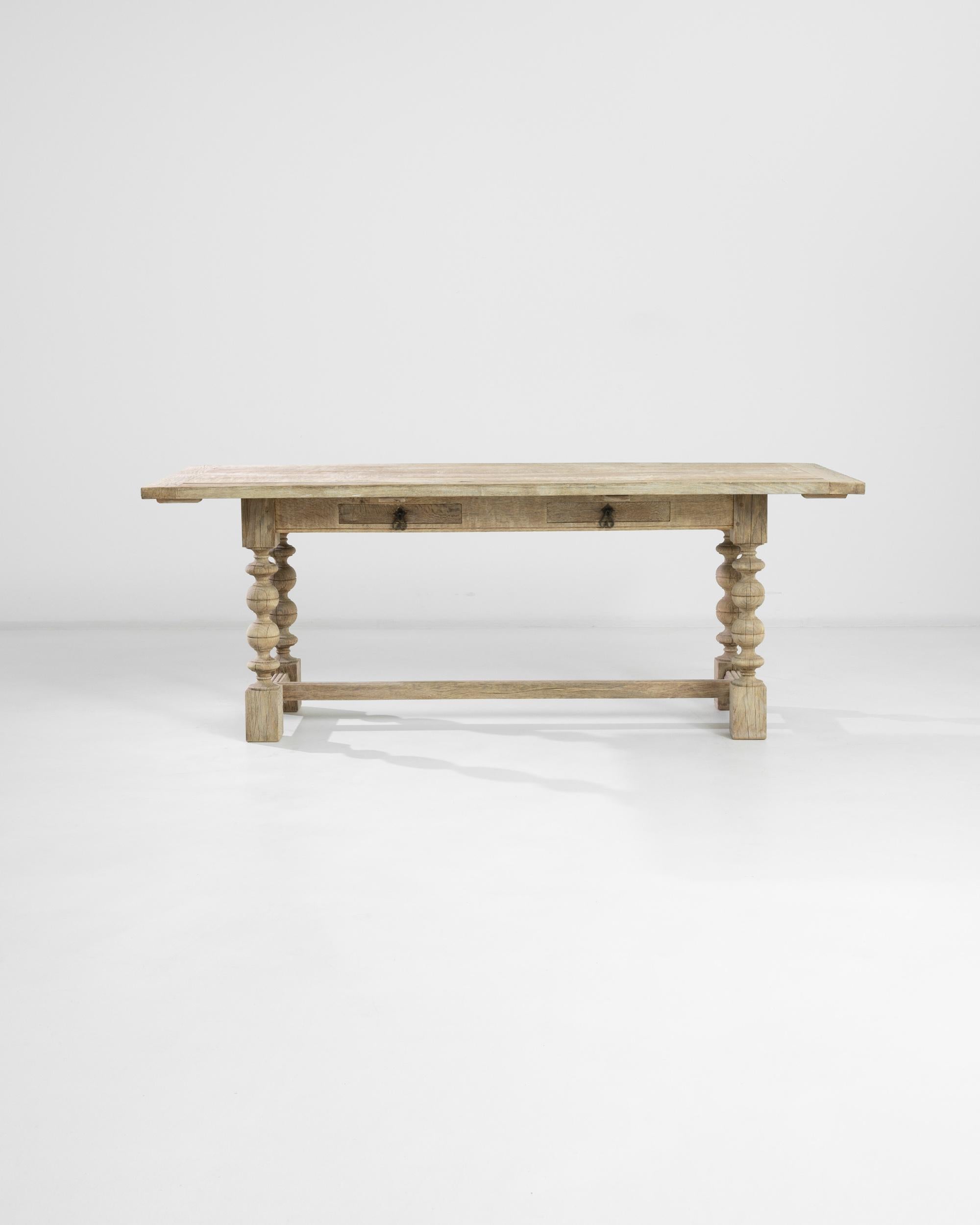 A French oak dining table made circa 1900, updated in our atelier with a bleached finish. The flawless bulb-shaped carvings of the turned legs set off the rectangular structure of the base with a side stretcher. The apron houses two shallow drawers