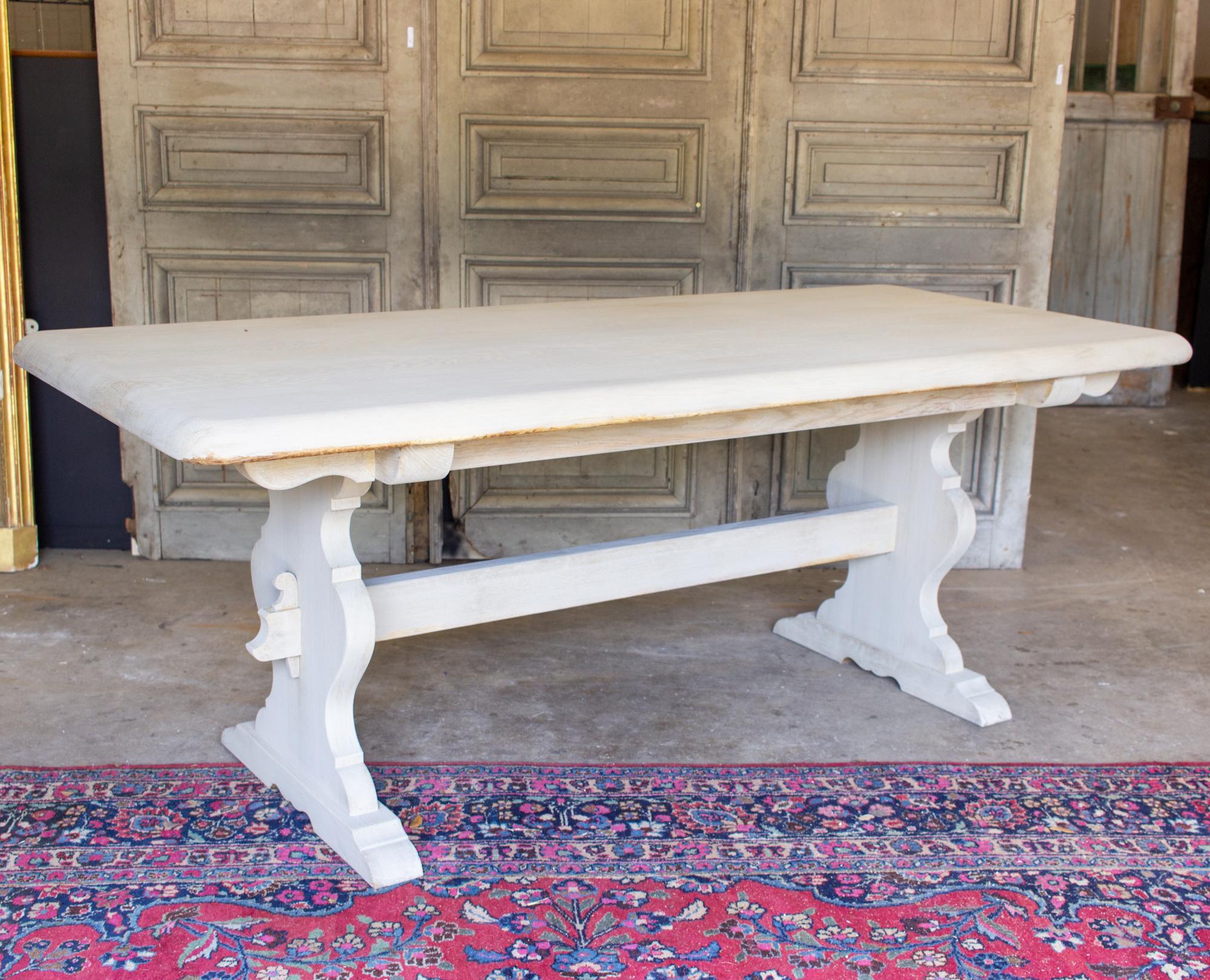 This is a beautiful, antique French oak trestle-style dining table with a light greige wash finish. The table is perfect for casual dining, or perhaps in a covered, outdoor space for entertaining. Measuring just over 6.5-feet long, it will easily