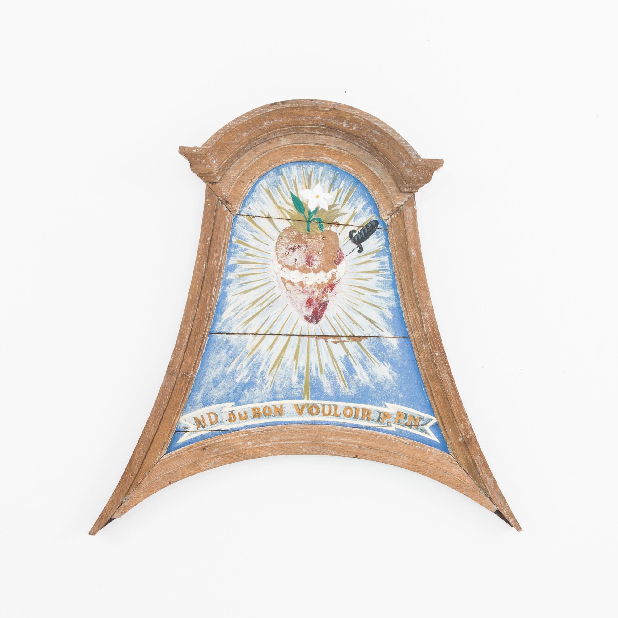 A wooden wall ornament from France, circa 1900. This antique ornament oozes into a surprising pointed shape, handcrafted in oak. Emblazoned with a bleeding heart emblem, and the cryptic slogan “ND du Bon Valor P.P.N.”