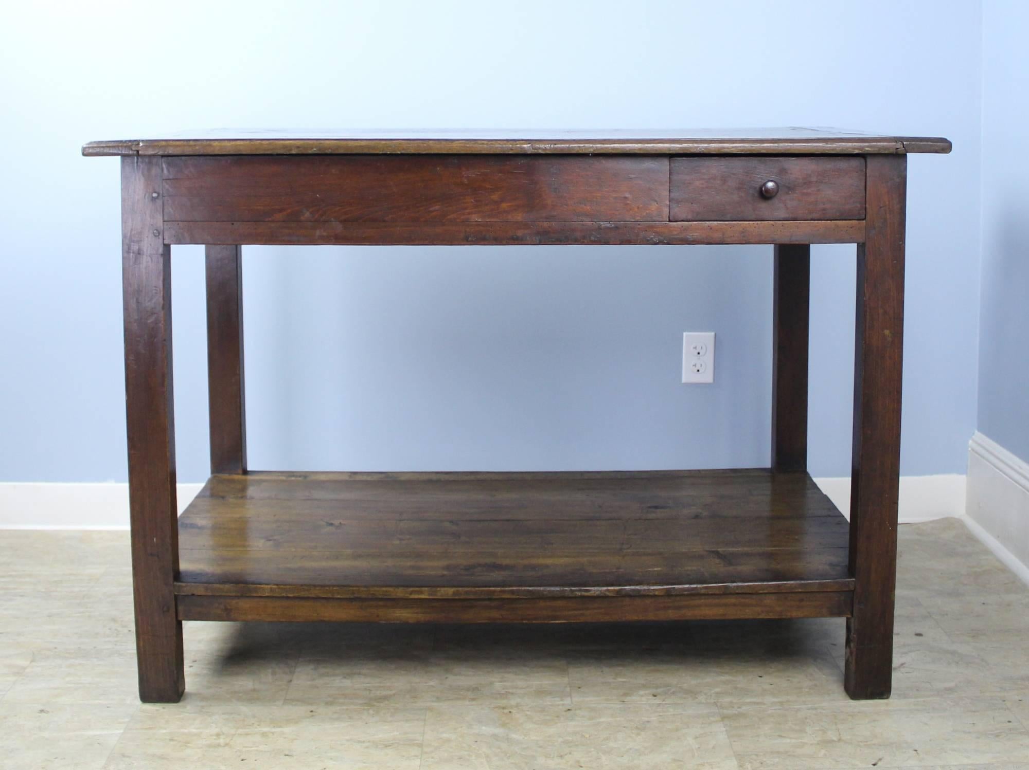 A highly versatile work station or table in dark oak. At 35 inches high, this piece would pair nicely with raised stools on both sides as a stylish work surface. Or just right to stand at in the kitchen. Apron height is 29 inches. Two small drawers