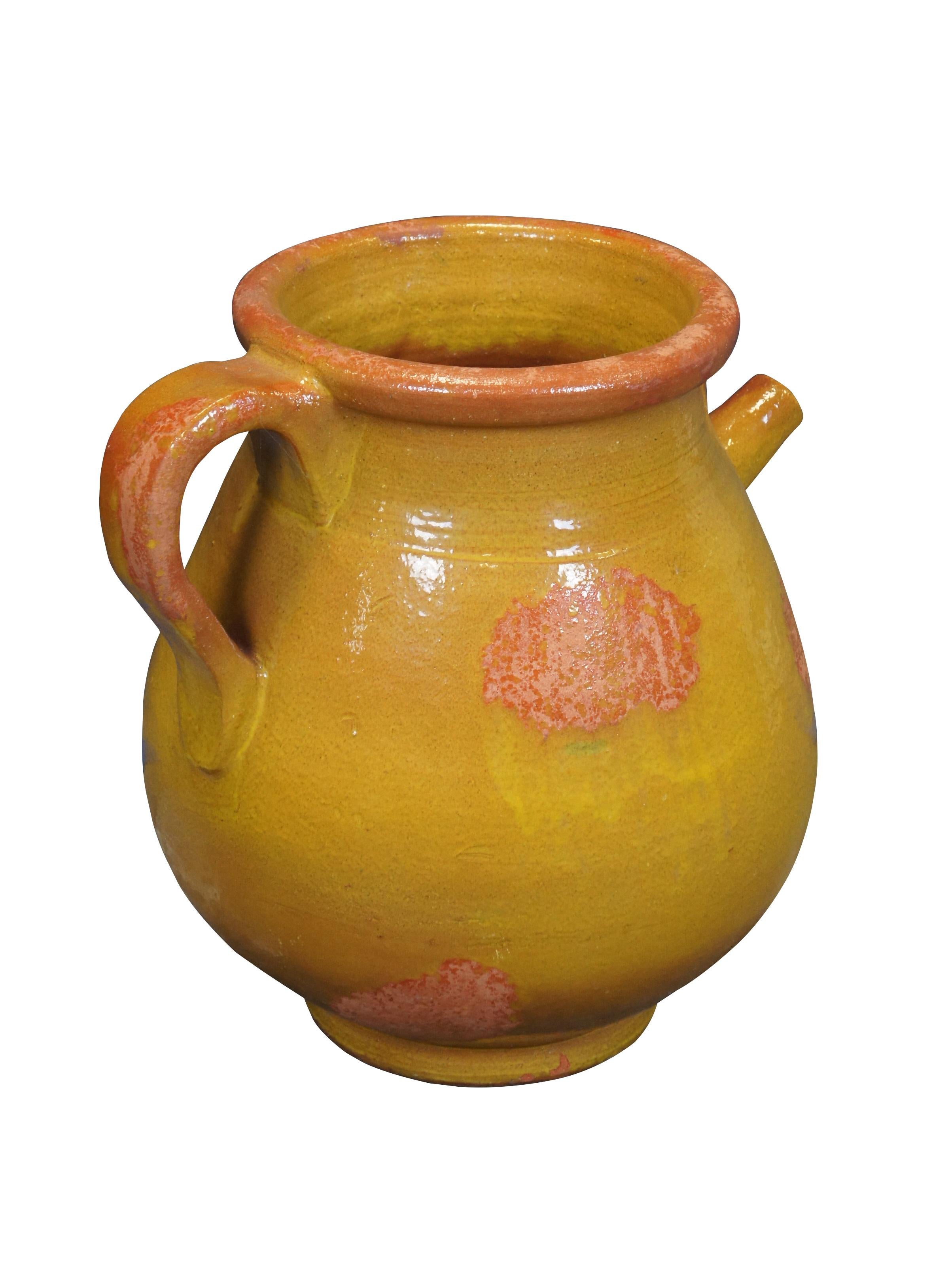 Antigua jarra de aceite de oliva/agua de terracota hecha a mano en Francia, de forma redonda con base de pie, borde moldeado, asa grande, pitorro estrecho, acabada en esmalte amarillo con detalles naranjas.

Dimensiones:
19