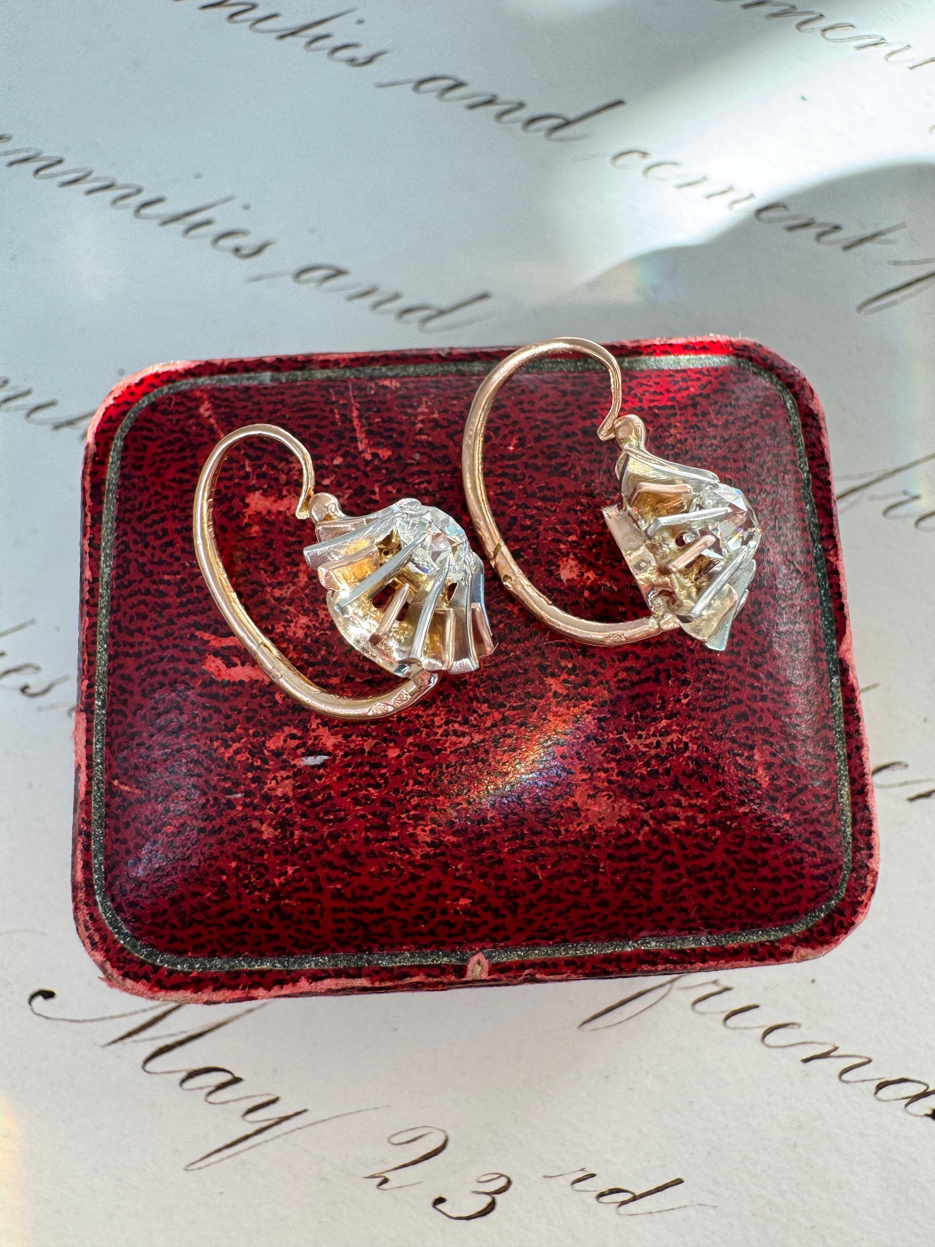 Hailing from late 19th century France, come these ultra-sparkly old mine-cut diamond sunburst dormeuses. A pair of shimmering old mine-cut diamonds, weighing .52 and .62 carats, are held high in 16 slender 18 karat rose gold and platinum prongs,
