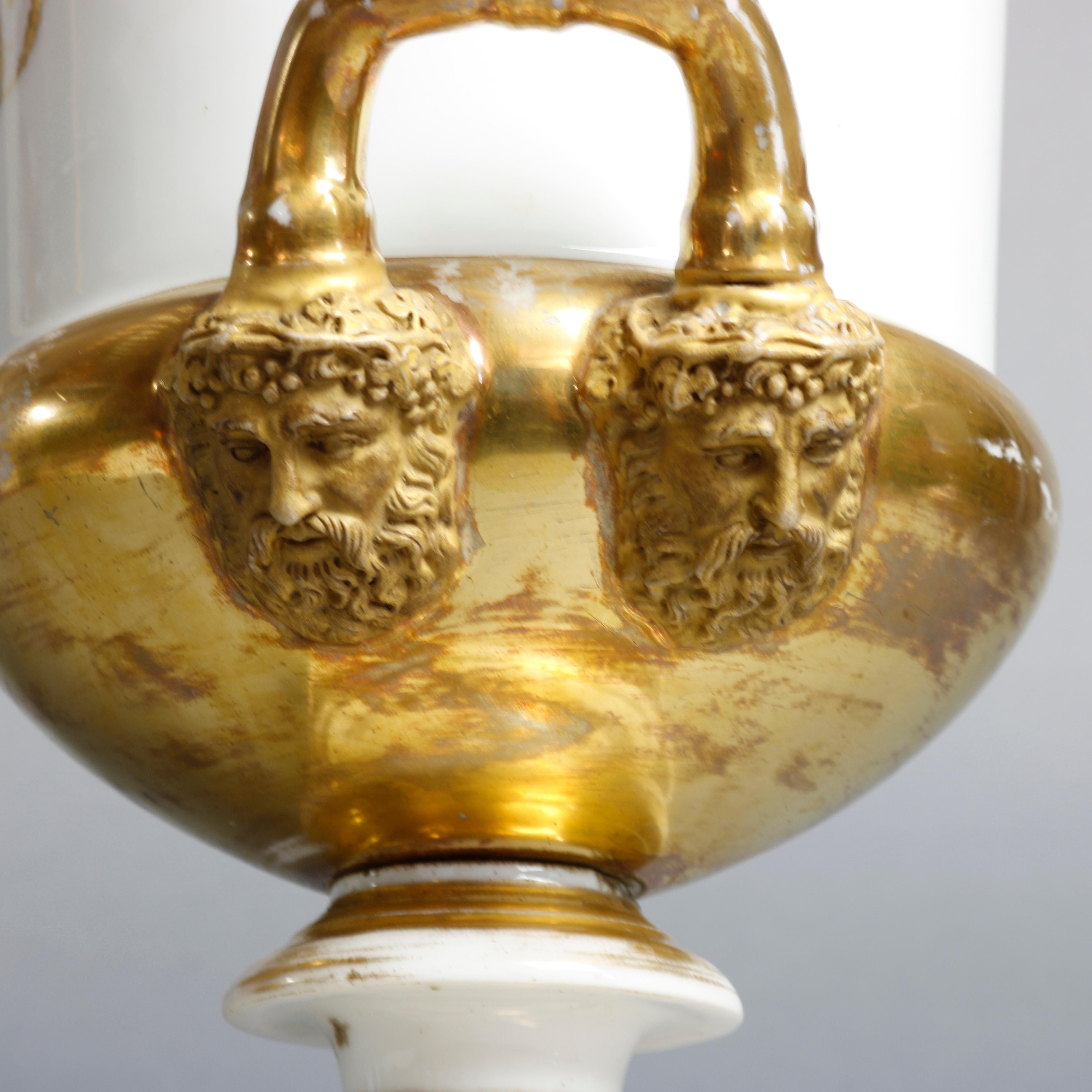 Antique French Old Pairs classical urns offer porcelain construction with double handles having Grecian faces, gilt highlights throughout with scrolled insignia on front possible 
