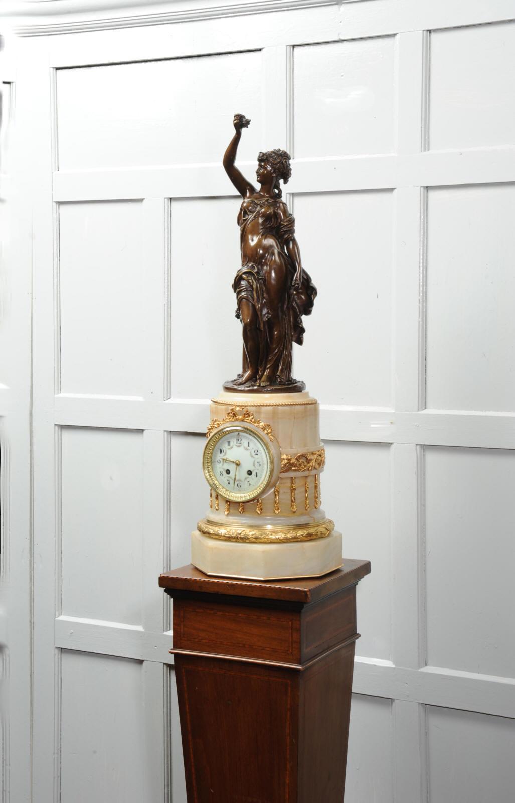 A stunning antique French clock circa 1890, the large ormolu mounted onxy columnar plinth housing the movement by Japy Freres and the superb antique bronze figure by sculptor Hippolyte Francois Moreau (1832-1927). The figure is La Rosé, she holds a