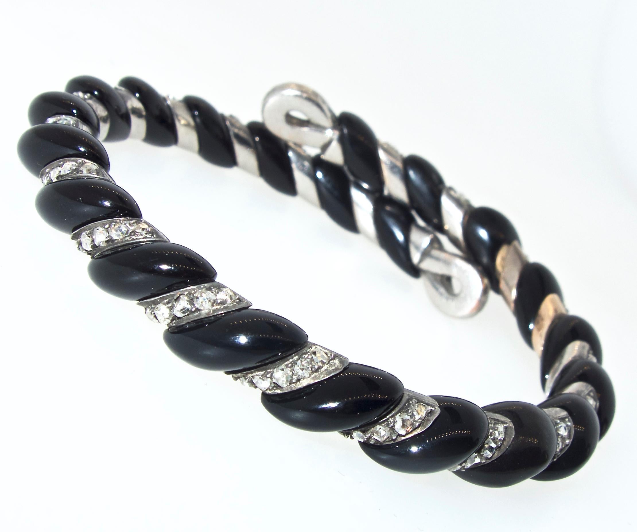 French and bearing old French hallmarks, this bracelet of fancy cut onyx and 125 old rose cut diamonds in a twist like motif is to be worn right at the wrist.  It has an internal spring so that it opens easily and fits just about any wrist size. 