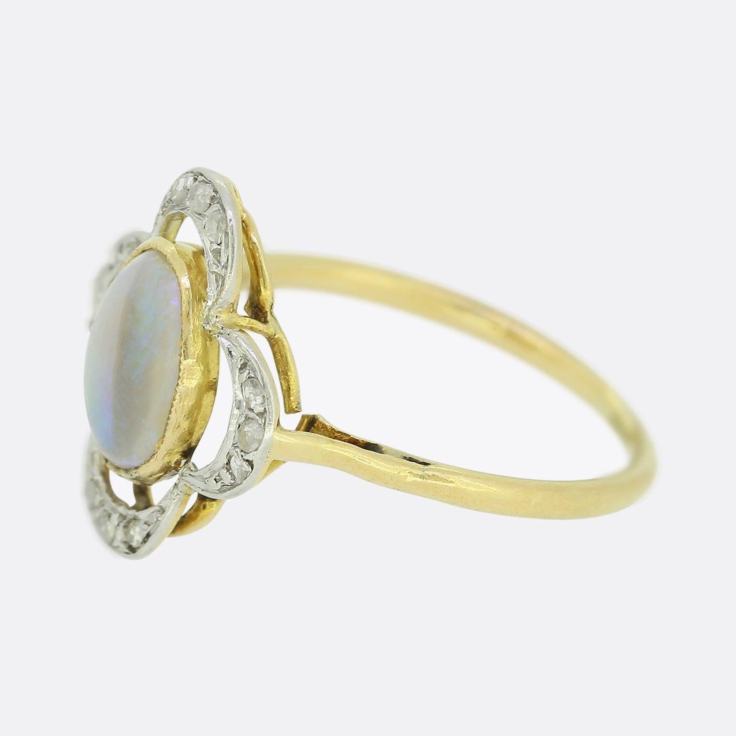 This is an 18ct yellow gold antique opal and diamond ring. The central opal features a lovely play of colour and is surrounded by a border of rose cut diamonds, set in an elegant floral design. The ring features French assay marks and dates back to