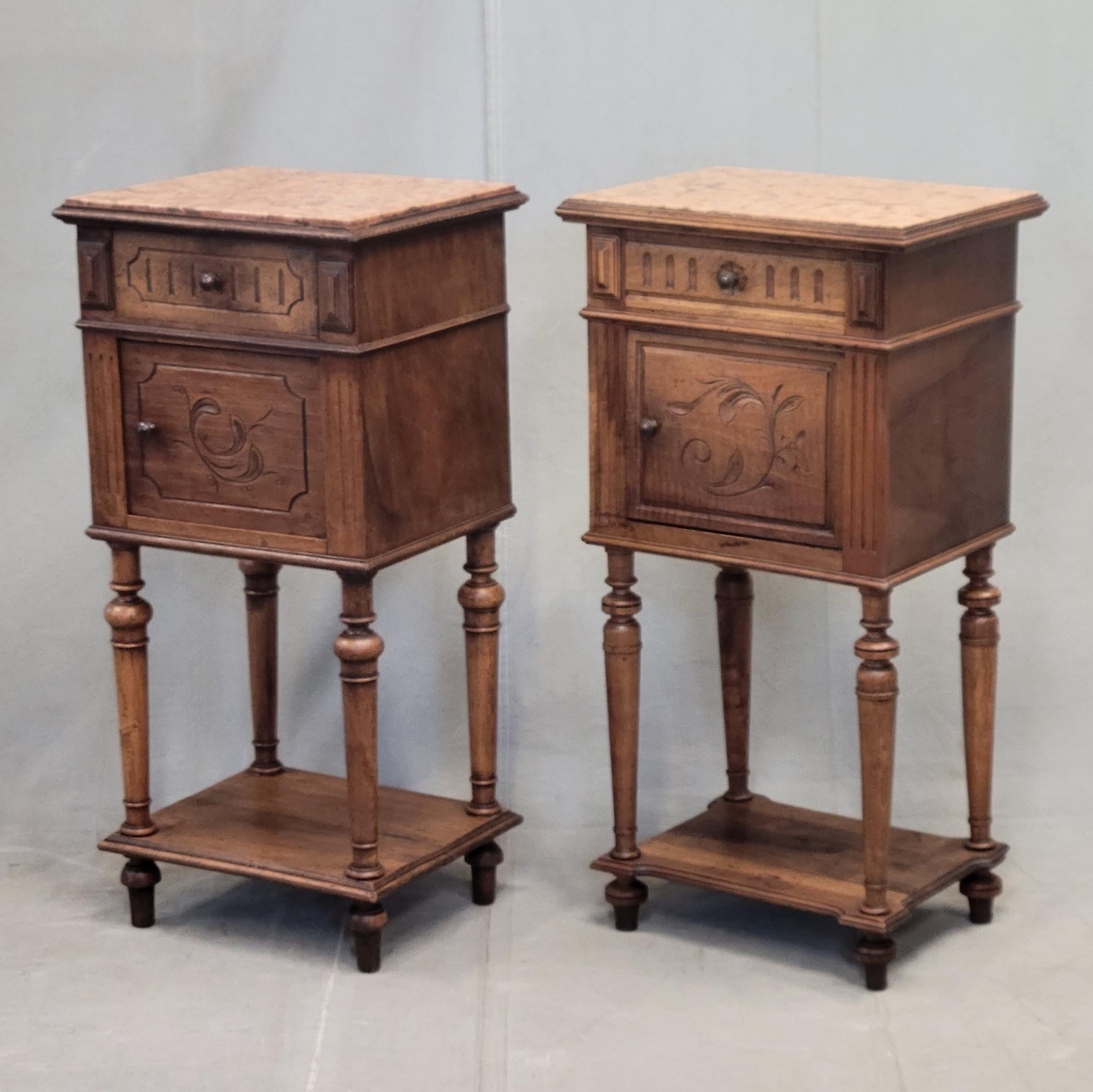 Una bella coppia di antichi comodini francesi o belgi degli anni '20 con splendidi piani in marmo italiano color terracotta. Si tratta di una coppia vicina... gli intagli ornamentali, la ferramenta e le dimensioni sono leggermente diverse. Entrambi